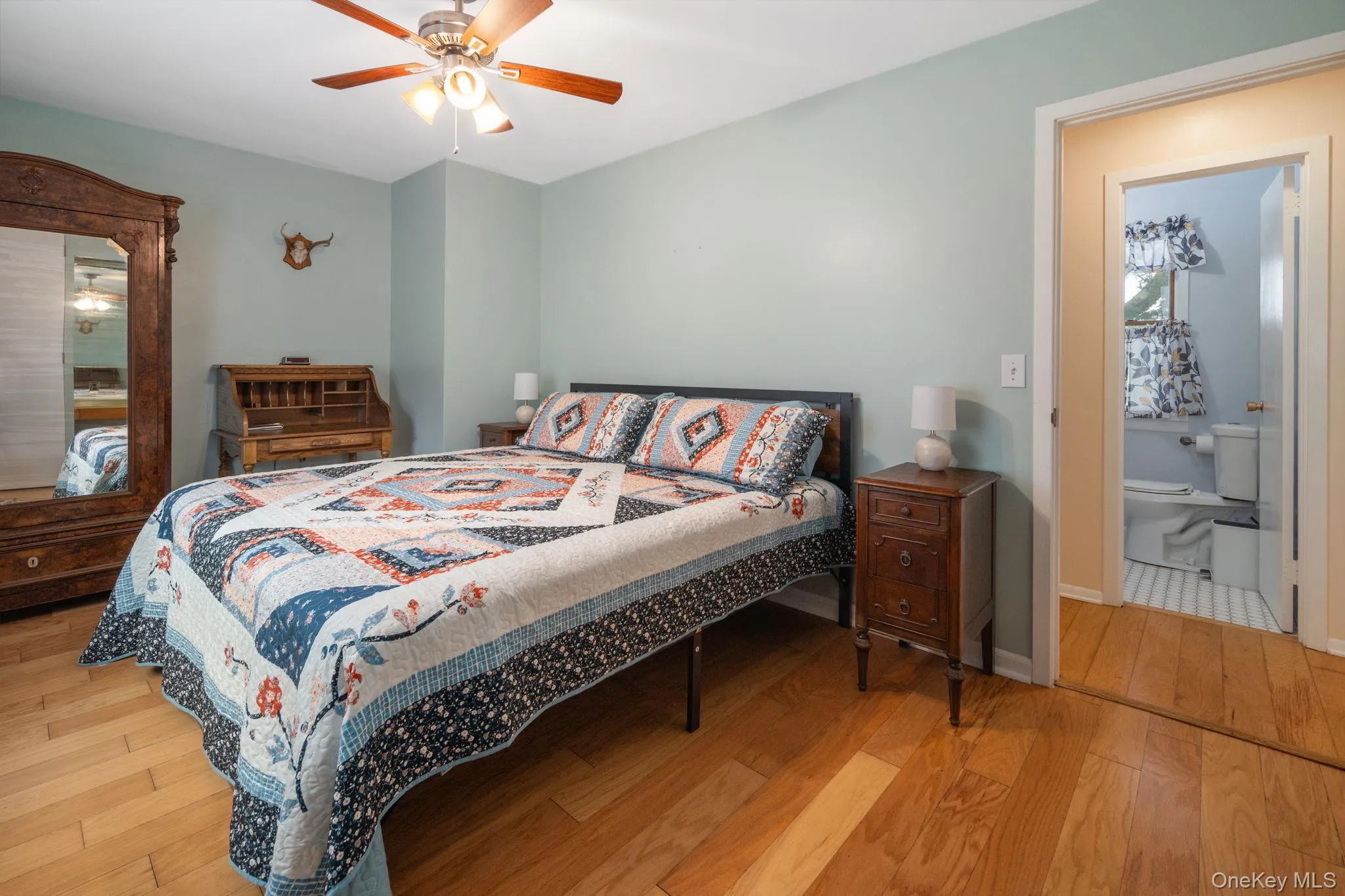Hardwood-style flooring, a ceiling fan with integrated lighting, and an attached private bathroom Hardwood-style flooring, a ceiling fan with integrated lighting, and an attached private bathroom
