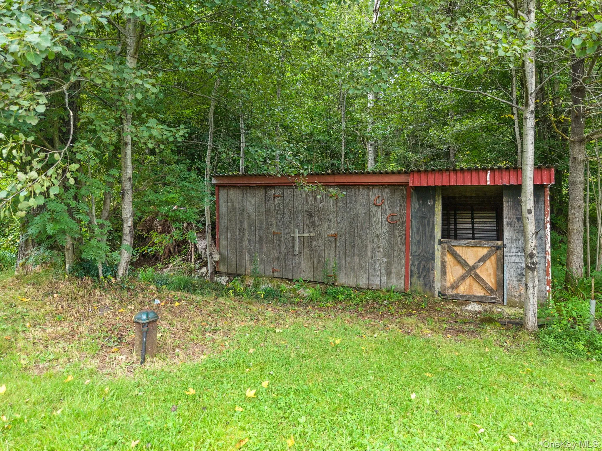 Wood-sided outbuilding with a corrugated metal roof and a wooden stable door Wood-sided outbuilding with a corrugated metal roof and a wooden stable door