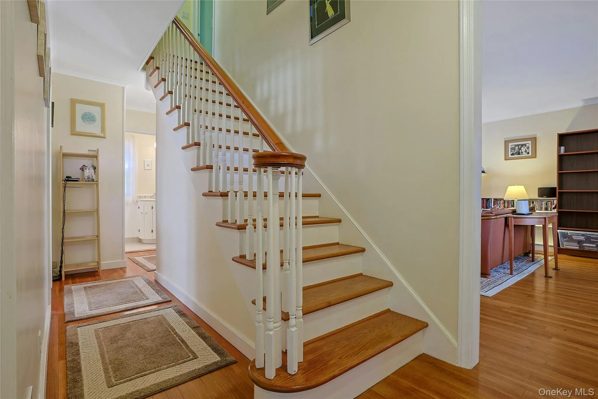 Entry showcasing hardwood flooring, a traditional staircase with white balusters, wood stairs and handrail, entry to the Living Room and the hallway leading to the Powder Room. Entry showcasing hardwood flooring, a traditional staircase with white balusters, wood stairs and handrail, entry to the Living Room and the hallway leading to the Powder Room.