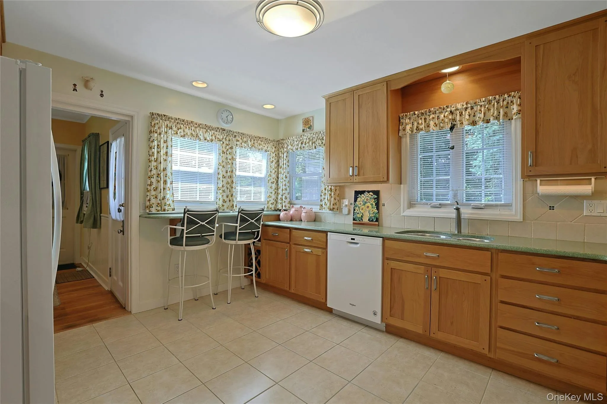 Kitchen featuring hickory wood cabinetry, quartz countertops, ceramic tile flooring, recessed lighting, and the breakfast bar overlooking the backyard. Kitchen featuring hickory wood cabinetry, quartz countertops, ceramic tile flooring, recessed lighting, and the breakfast bar overlooking the backyard.