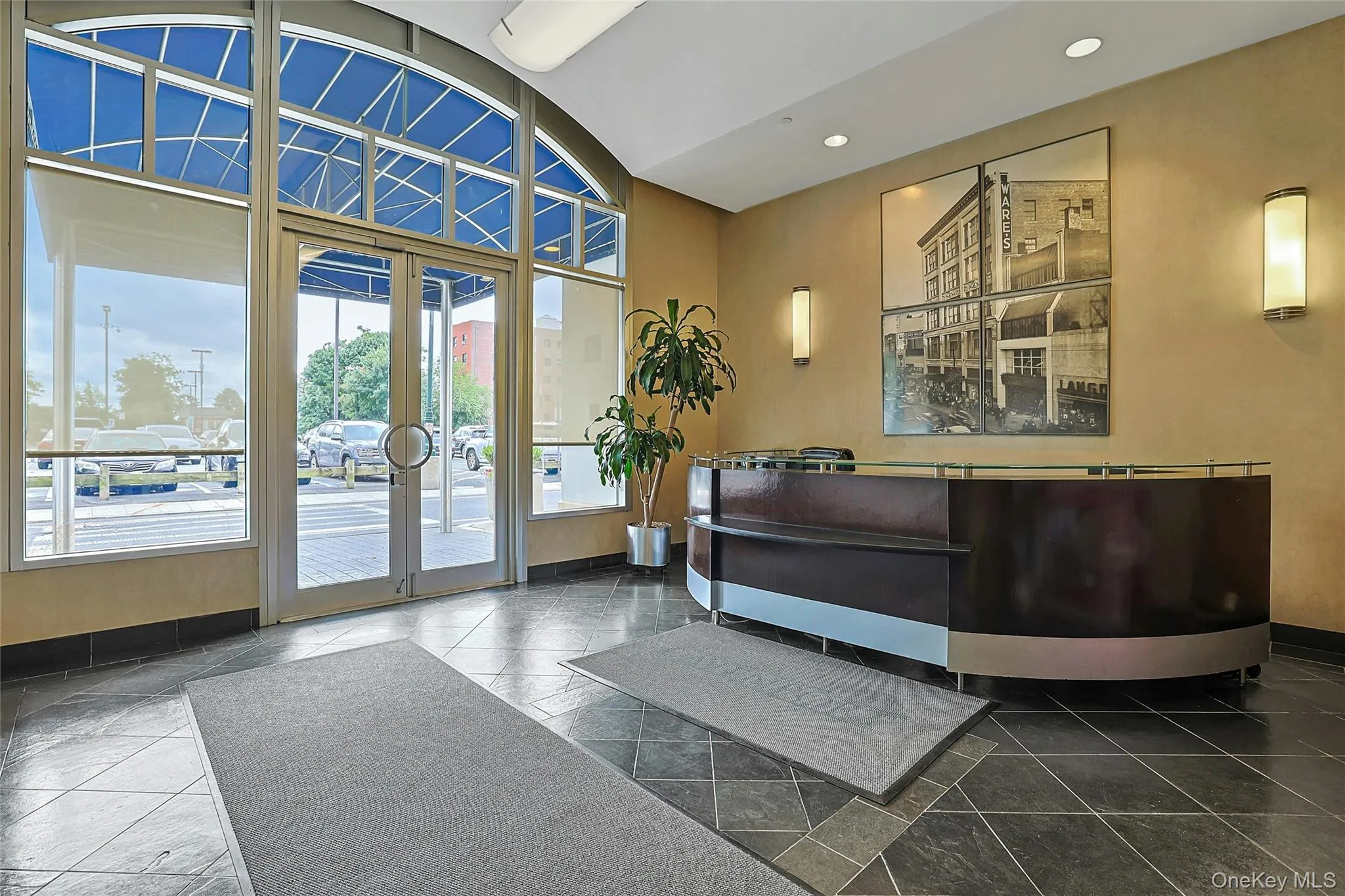 Inviting building lobby with doorman desk, large windows, and contemporary finishes. Inviting building lobby with doorman desk, large windows, and contemporary finishes.