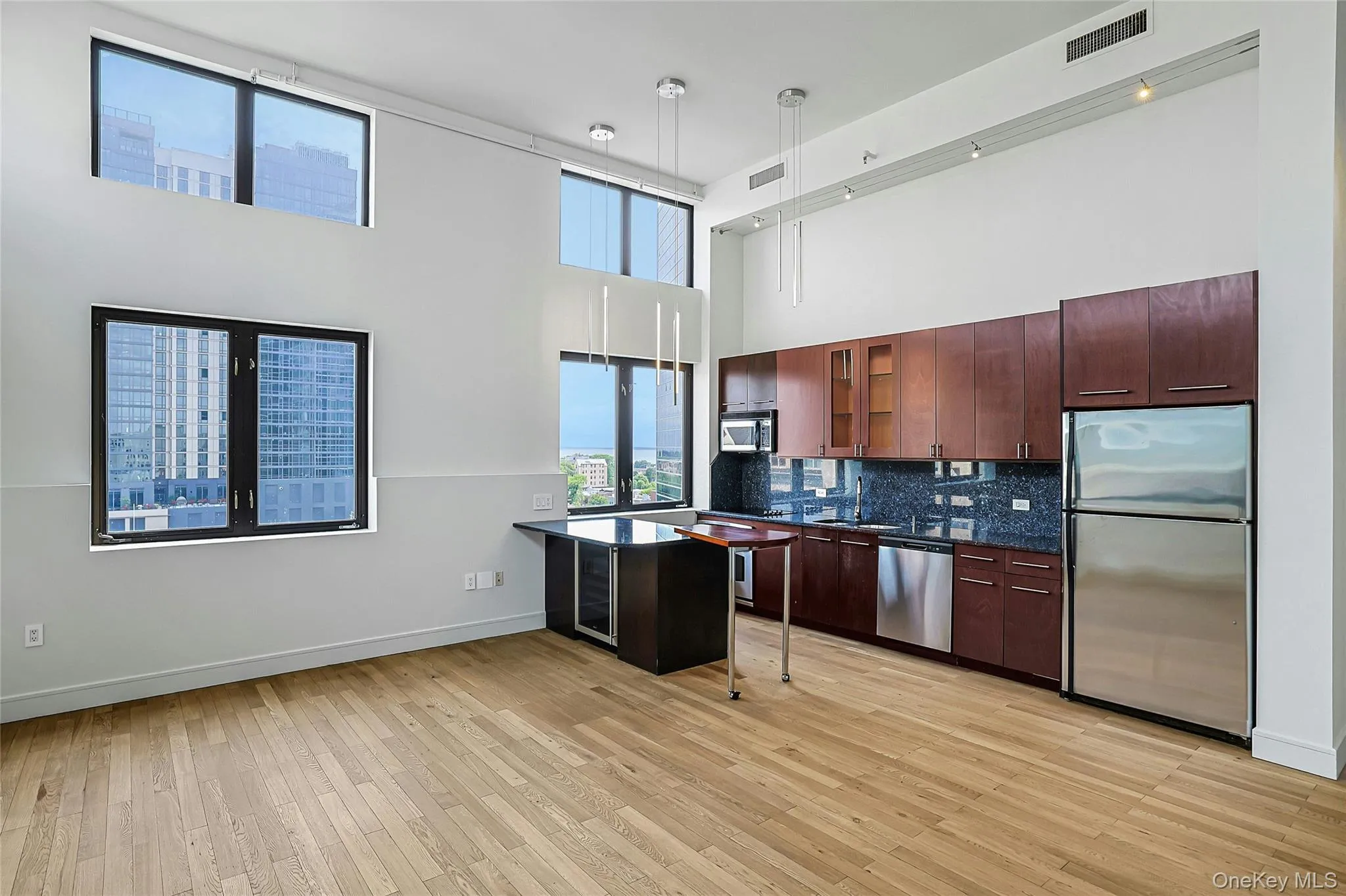 Modern open kitchen with rich wood cabinetry, stone countertops, stainless steel appliances, and center island. Modern open kitchen with rich wood cabinetry, stone countertops, stainless steel appliances, and center island.