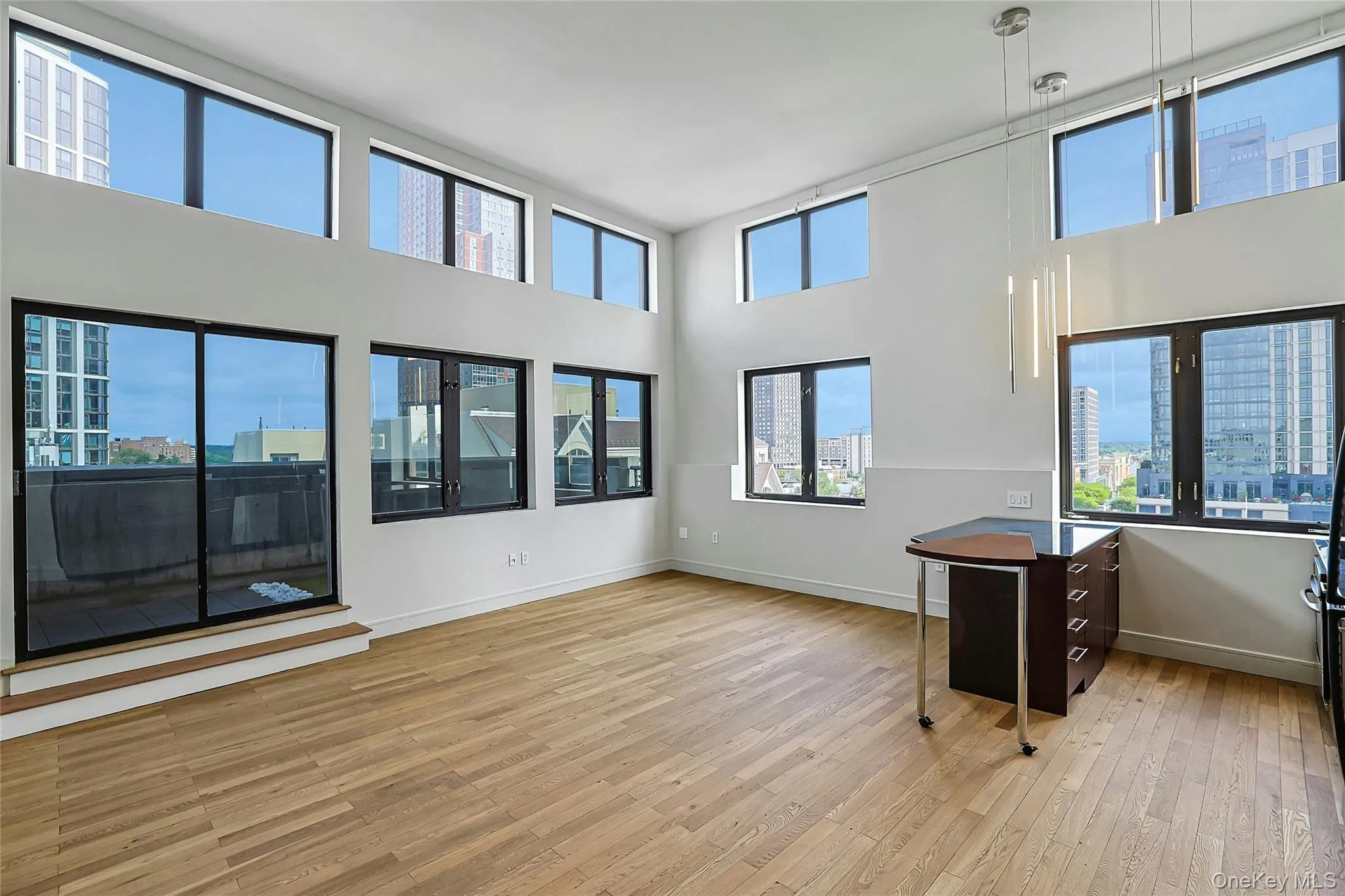 Expansive open-concept living and dining space with soaring ceilings, hardwood floors, and walls of windows. Expansive open-concept living and dining space with soaring ceilings, hardwood floors, and walls of windows.
