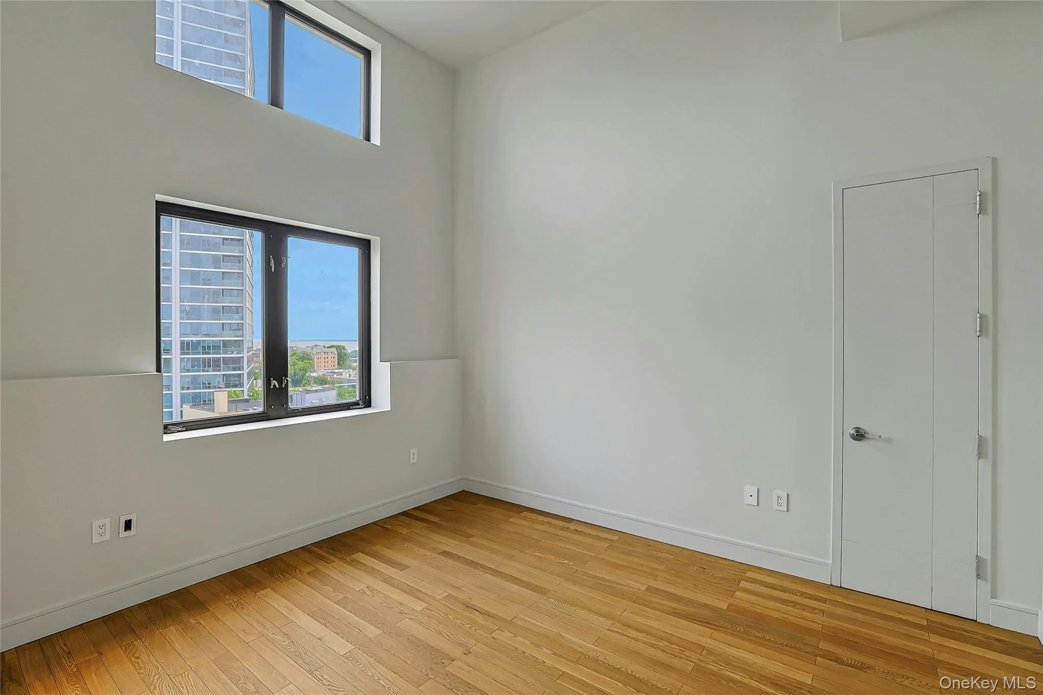 Spacious bedroom with soaring ceilings, hardwood floors, and oversized windows. Spacious bedroom with soaring ceilings, hardwood floors, and oversized windows.