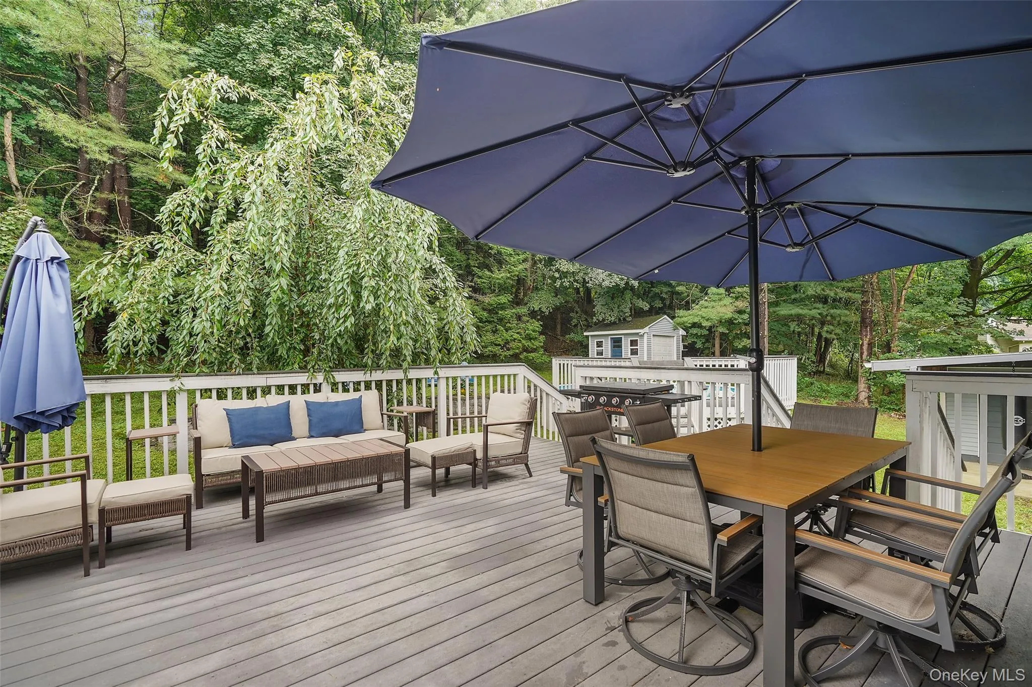 Spacious outdoor deck with a gray composite surface, white railing, and a storage shed Spacious outdoor deck with a gray composite surface, white railing, and a storage shed