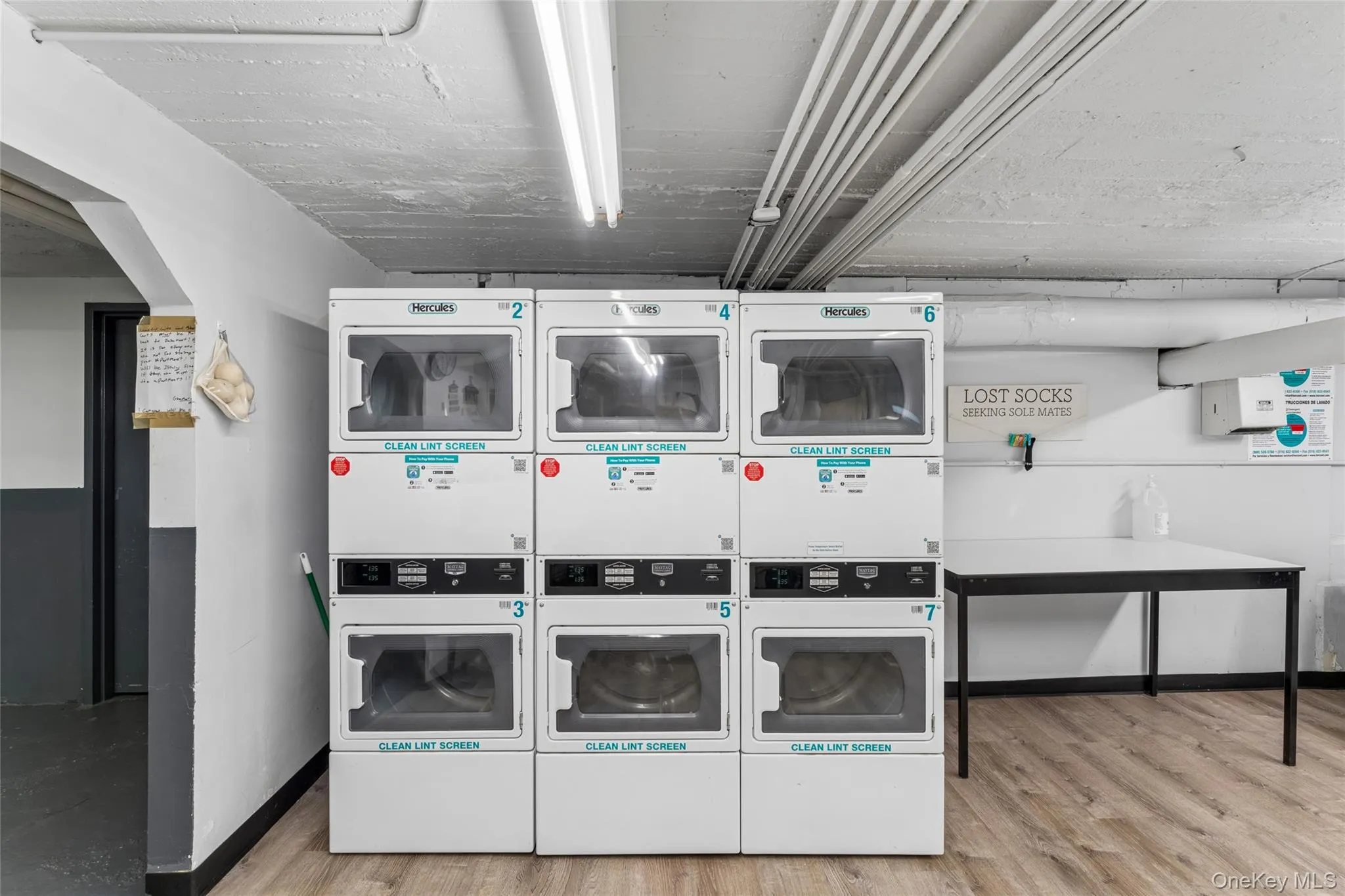 On-site laundry facility featuring multiple commercial-grade washers and dryers, wood-finish flooring, and ample lighting On-site laundry facility featuring multiple commercial-grade washers and dryers, wood-finish flooring, and ample lighting