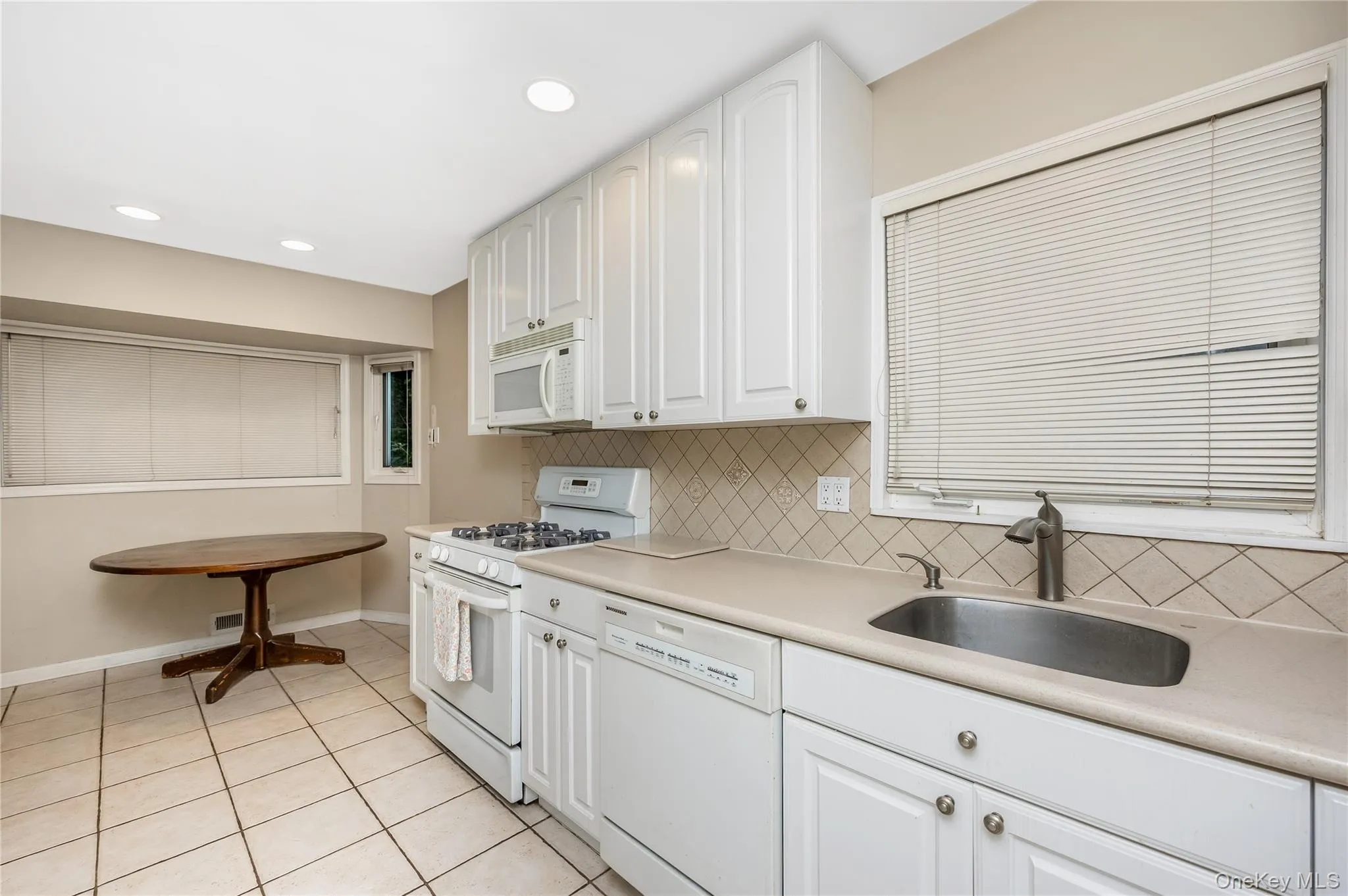 Eat in Kitchen featuring white cabinetry, tile backsplash, stainless steel sink, and recessed lighting Eat in Kitchen featuring white cabinetry, tile backsplash, stainless steel sink, and recessed lighting