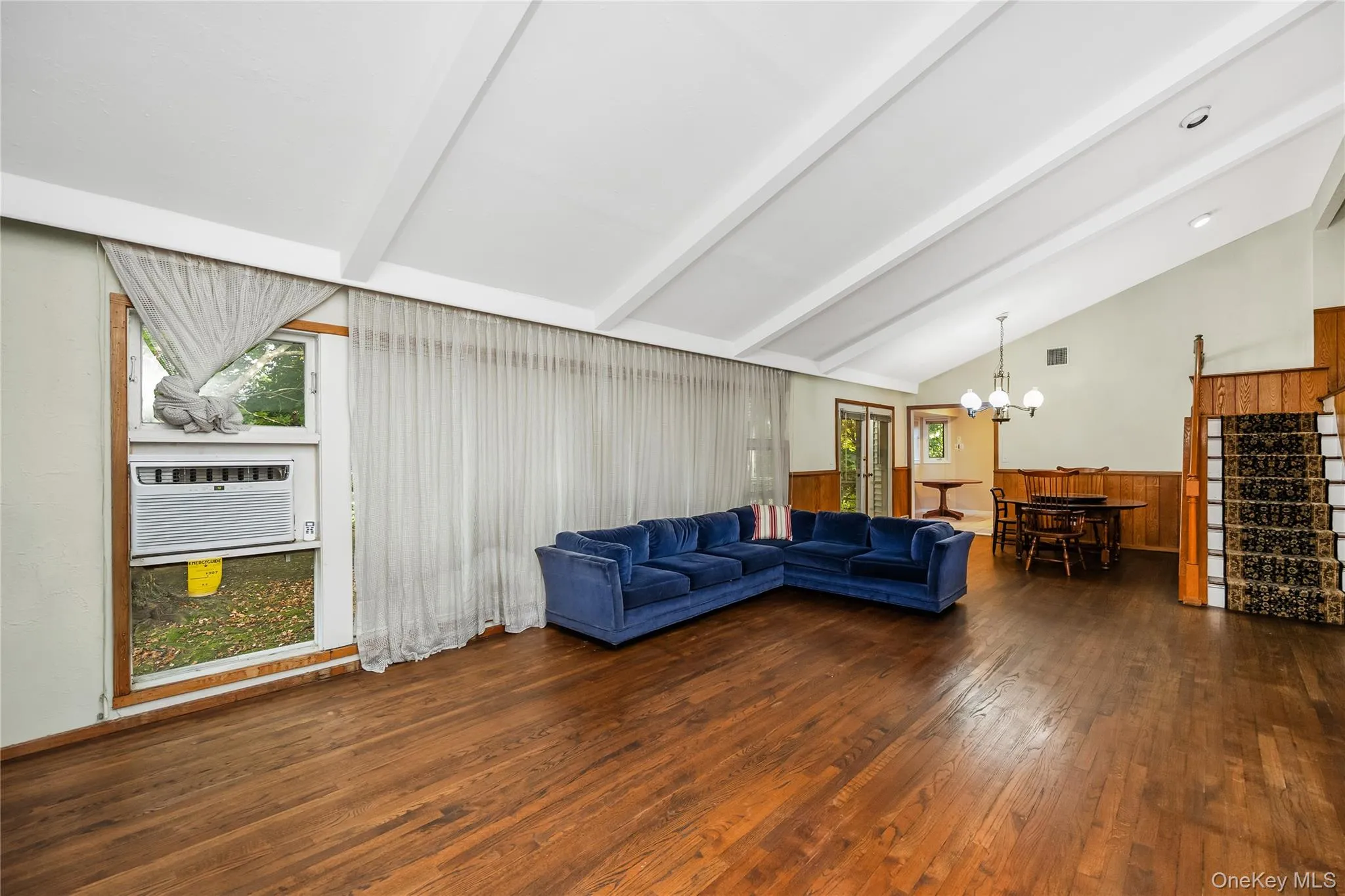 Vaulted ceiling with exposed beams, brick fireplace, wood-finish flooring, wood panel accent walls, and recessed lighting Vaulted ceiling with exposed beams, brick fireplace, wood-finish flooring, wood panel accent walls, and recessed lighting