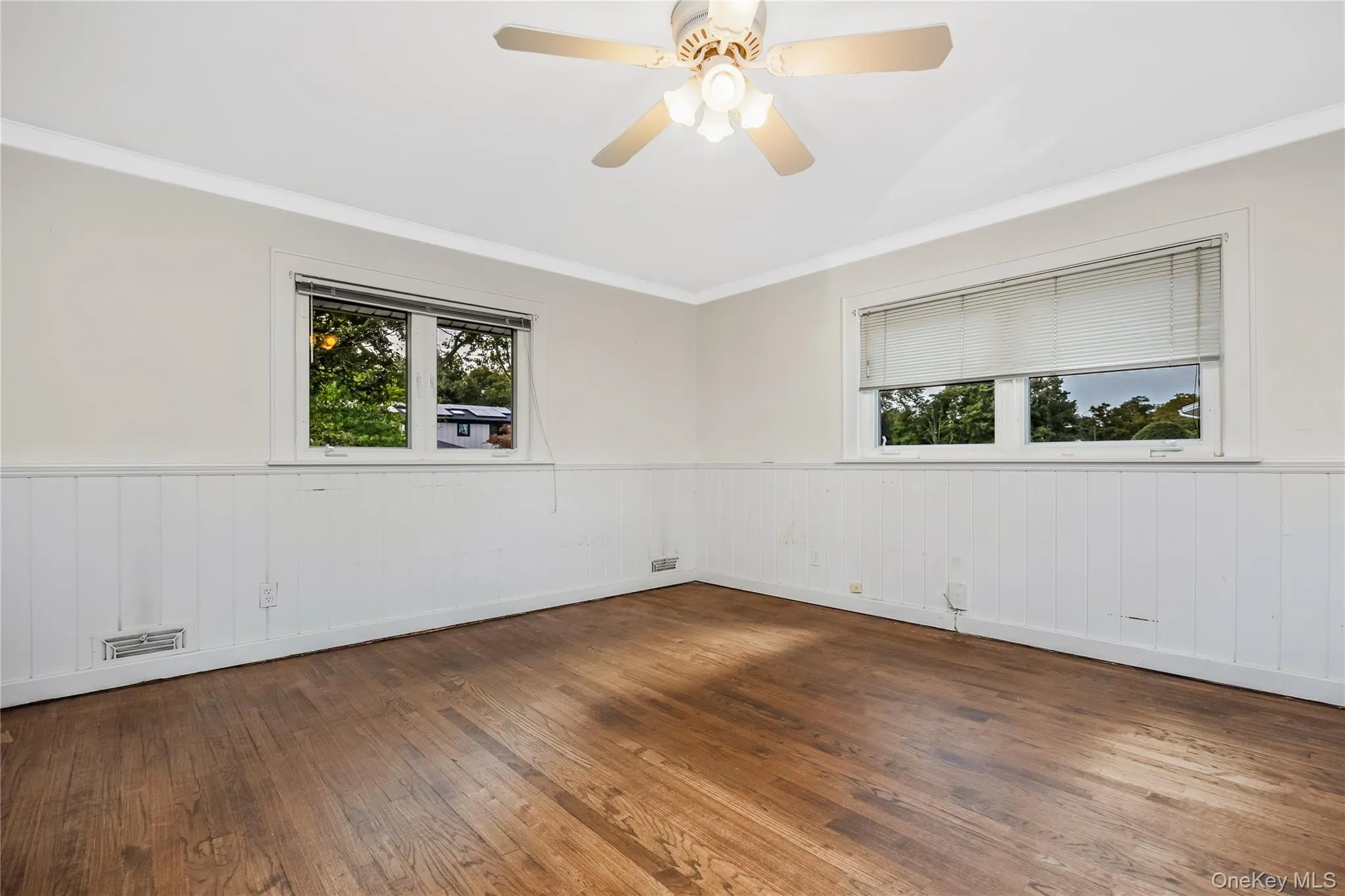 Hardwood flooring, painted wainscoting, crown molding, and a ceiling fan with integrated lighting Hardwood flooring, painted wainscoting, crown molding, and a ceiling fan with integrated lighting