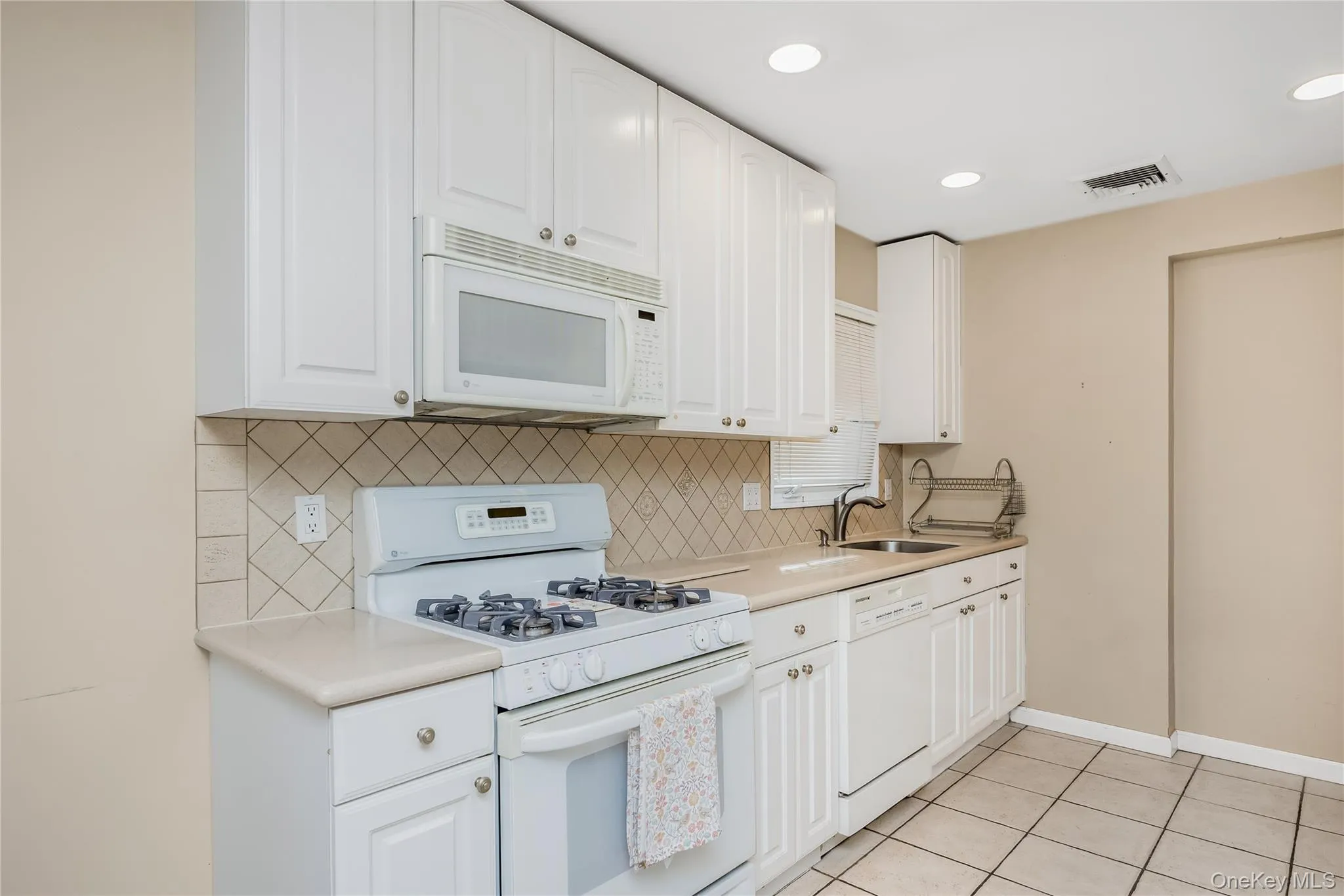 Eat in Kitchen featuring white cabinetry, tile backsplash, stainless steel sink, and recessed lighting Eat in Kitchen featuring white cabinetry, tile backsplash, stainless steel sink, and recessed lighting