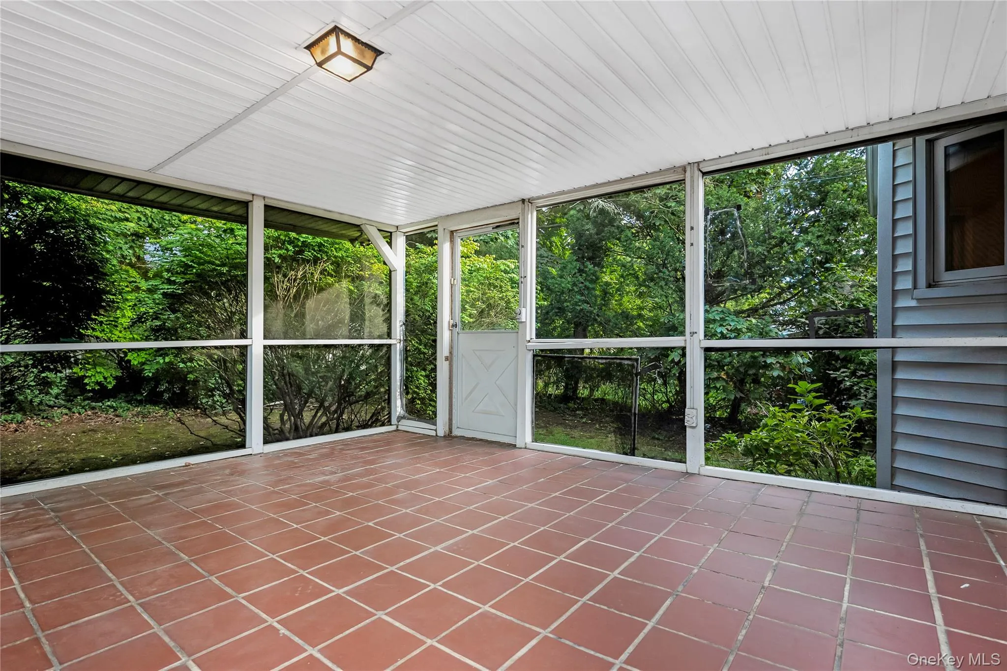 Screened porch featuring terracotta-style tile flooring, white paneled ceiling, and exterior entry door Screened porch featuring terracotta-style tile flooring, white paneled ceiling, and exterior entry door