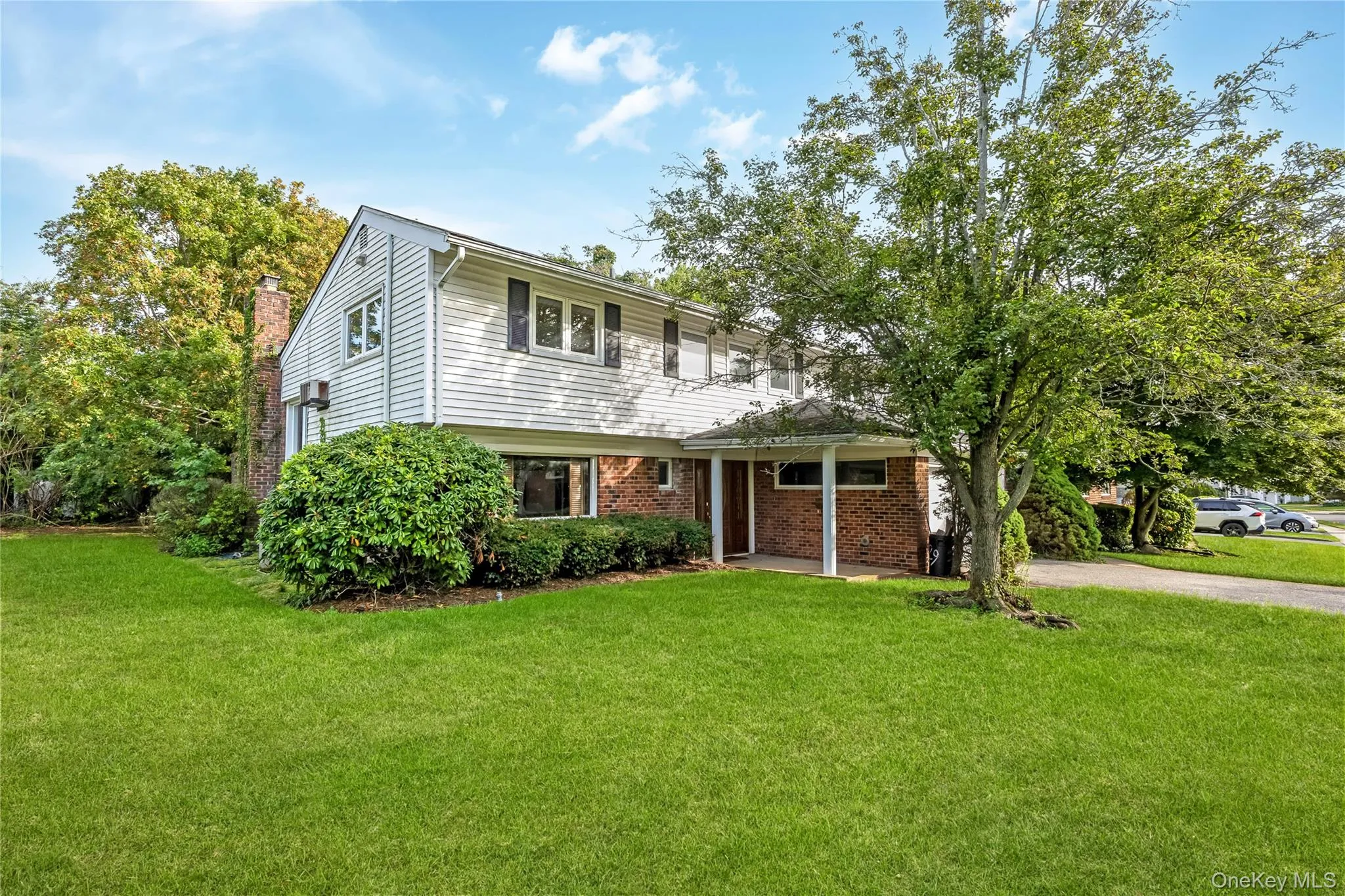 WELCOME HOME! Three-story residence featuring a front lawn, mature tree, attached two-car garage, and a covered entry. Grass enhanced WELCOME HOME! Three-story residence featuring a front lawn, mature tree, attached two-car garage, and a covered entry. Grass enhanced