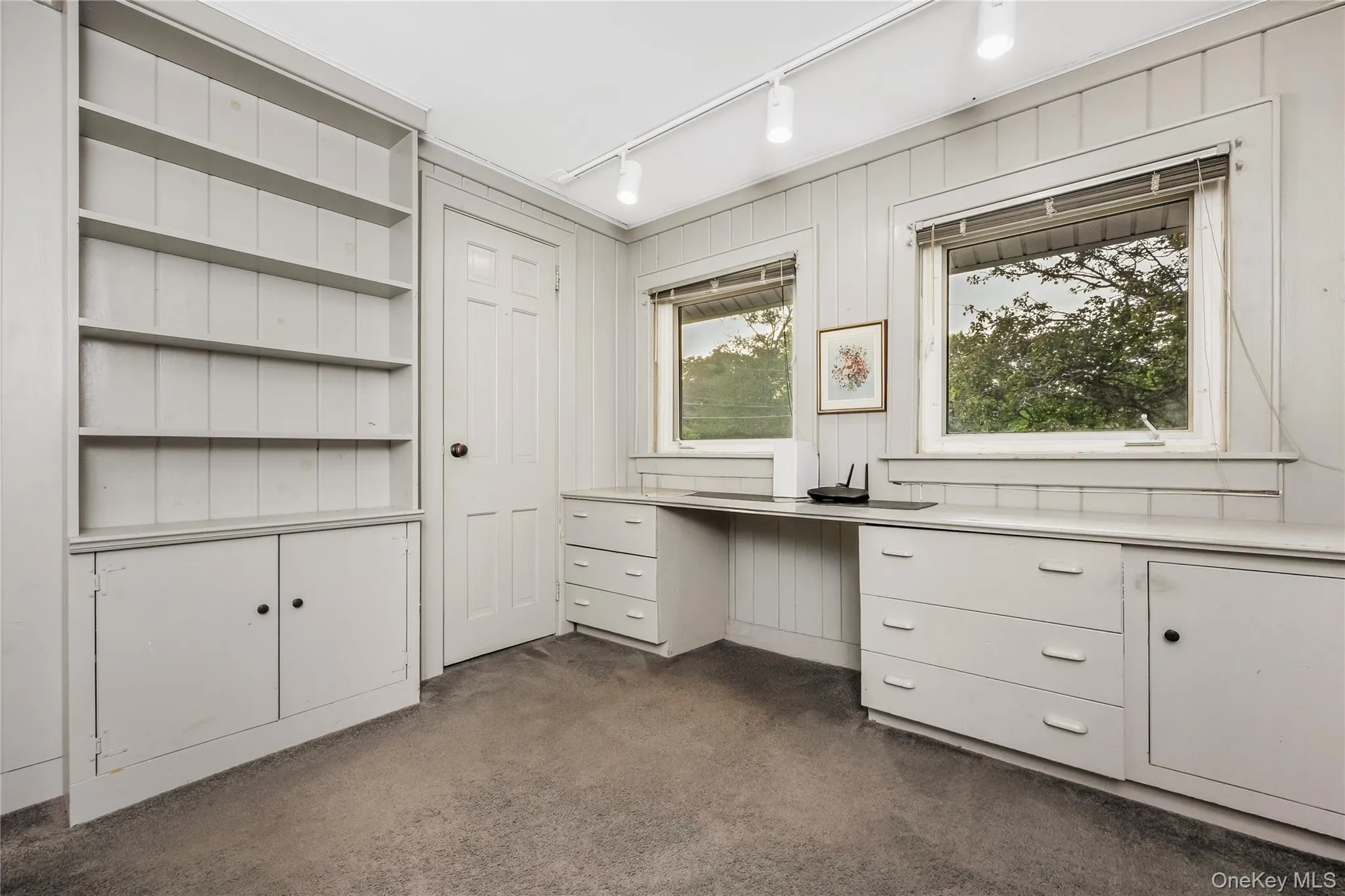 Built-in shelving, integrated desk, track lighting, and two windows Built-in shelving, integrated desk, track lighting, and two windows