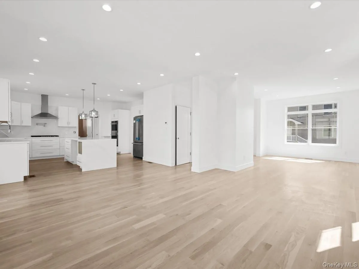 Contemporary kitchen with white cabinetry, stainless steel appliances, a center island with pendant lighting, and wood-finish flooring throughout Contemporary kitchen with white cabinetry, stainless steel appliances, a center island with pendant lighting, and wood-finish flooring throughout