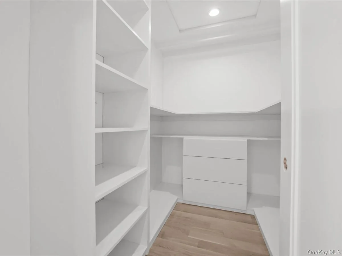 Built-in white shelving, integrated drawers, recessed ceiling light, and wood-finish flooring Built-in white shelving, integrated drawers, recessed ceiling light, and wood-finish flooring