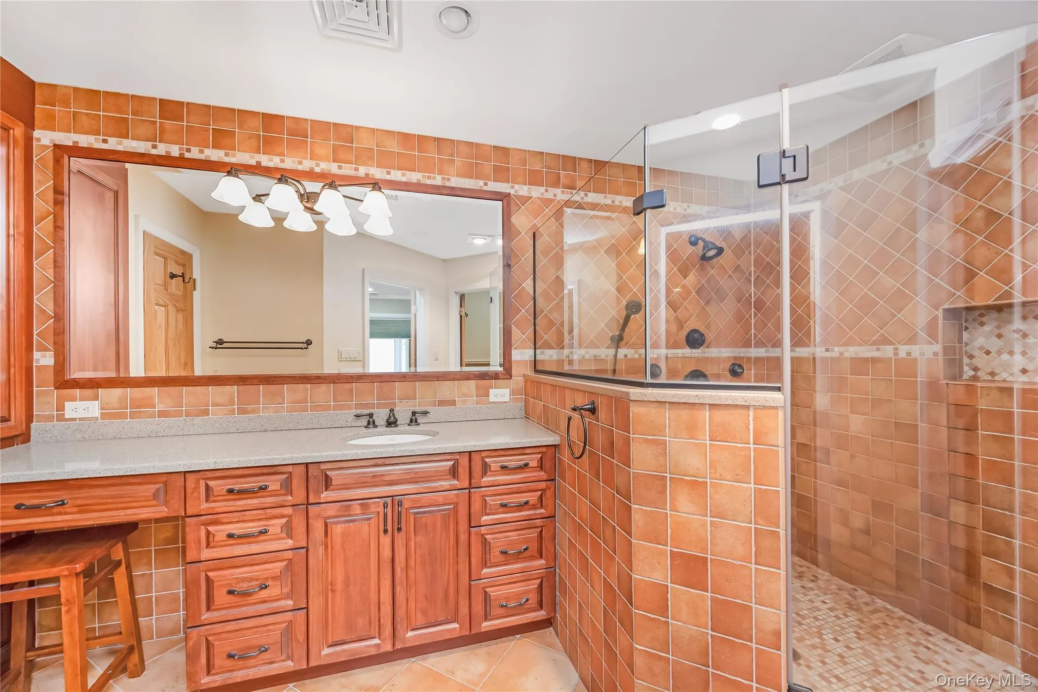 Primary Bath with oversized vanity and integrated sink, glass-enclosed shower, tiled walls, linen closet and a built-in shower niche Primary Bath with oversized vanity and integrated sink, glass-enclosed shower, tiled walls, linen closet and a built-in shower niche