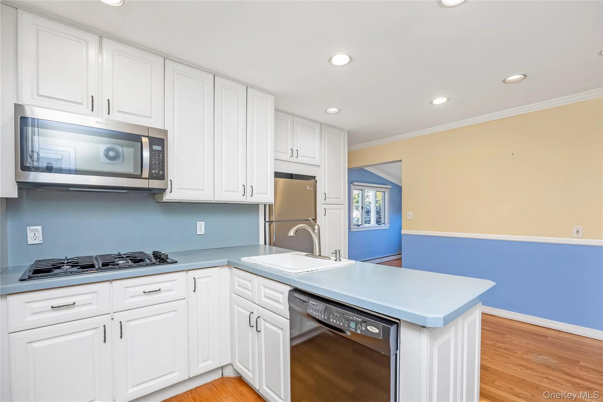 EIK with white cabinetry, wood-finish flooring, stainless steel appliances, built-in oven, and a gas cooktop EIK with white cabinetry, wood-finish flooring, stainless steel appliances, built-in oven, and a gas cooktop