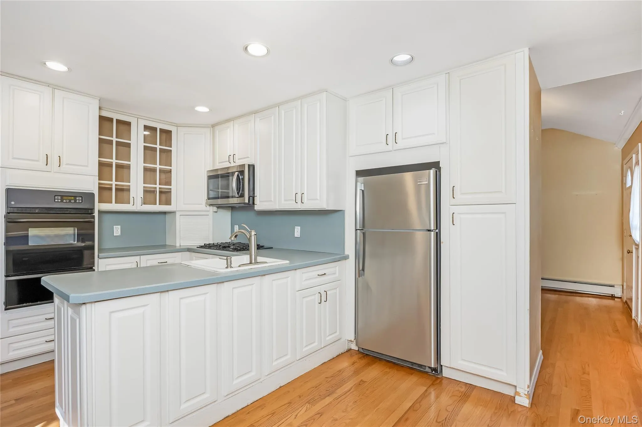 EIK with white cabinetry, wood-finish flooring, stainless steel appliances, built-in oven, and a gas cooktop EIK with white cabinetry, wood-finish flooring, stainless steel appliances, built-in oven, and a gas cooktop
