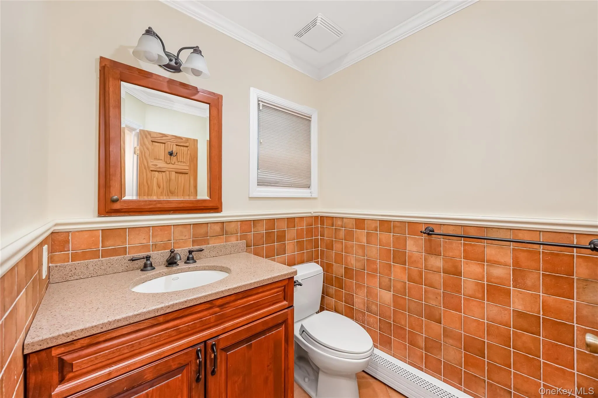 Primary Bath separate water closet with wood-finish vanity with an integrated sink, stone-finish countertop, and bronze-finish faucet Primary Bath separate water closet with wood-finish vanity with an integrated sink, stone-finish countertop, and bronze-finish faucet