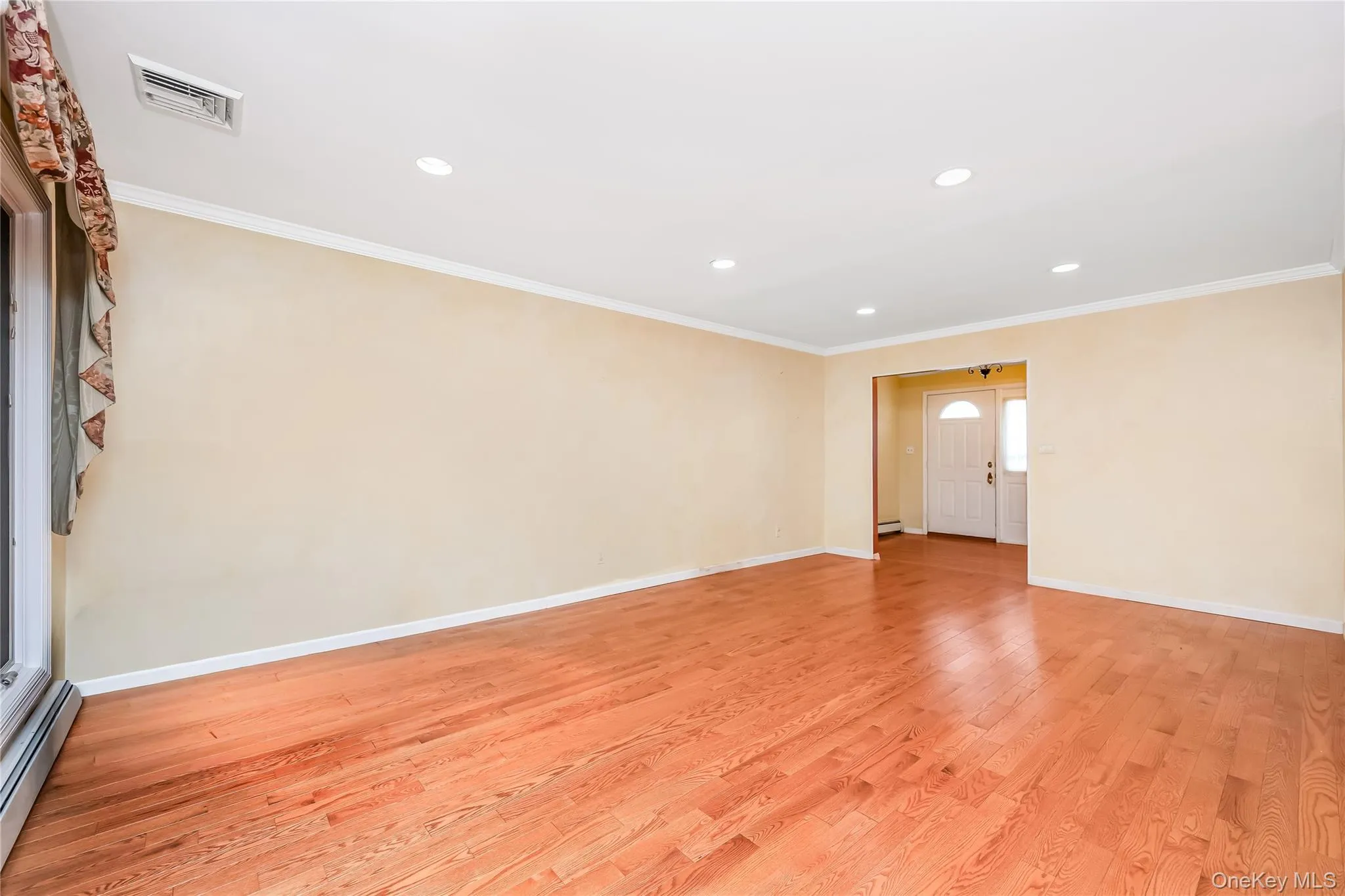 Living room access from entry foyer with hardwood flooring, recessed ceiling lighting and crown molding Living room access from entry foyer with hardwood flooring, recessed ceiling lighting and crown molding