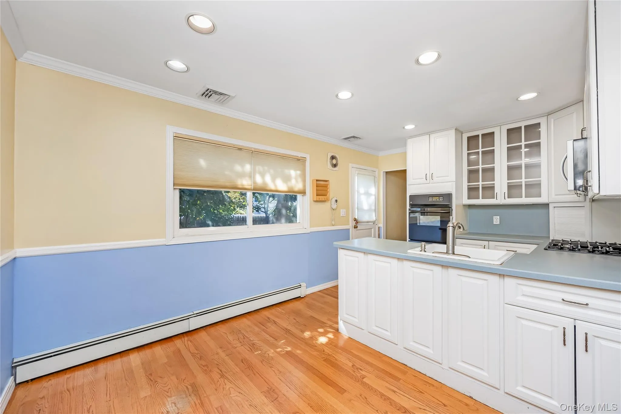 EIK with white cabinetry, wood-finish flooring, stainless steel appliances, built-in oven, and a gas cooktop EIK with white cabinetry, wood-finish flooring, stainless steel appliances, built-in oven, and a gas cooktop