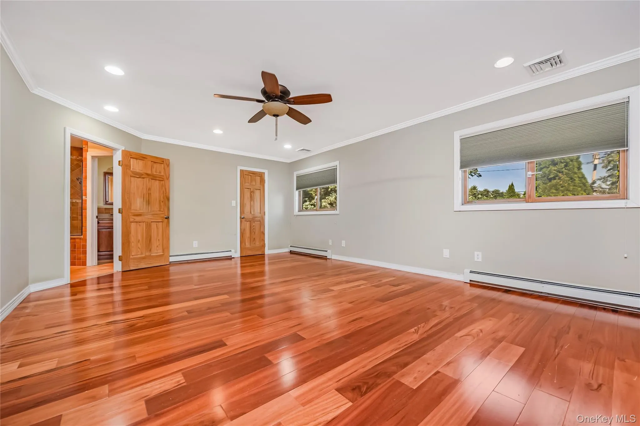Extended Primary bedroom with wood-finish flooring, 2 custom wic and a 3rd closet, multiple windows, recessed lighting, a ceiling fan and access to the huge primary bath Extended Primary bedroom with wood-finish flooring, 2 custom wic and a 3rd closet, multiple windows, recessed lighting, a ceiling fan and access to the huge primary bath
