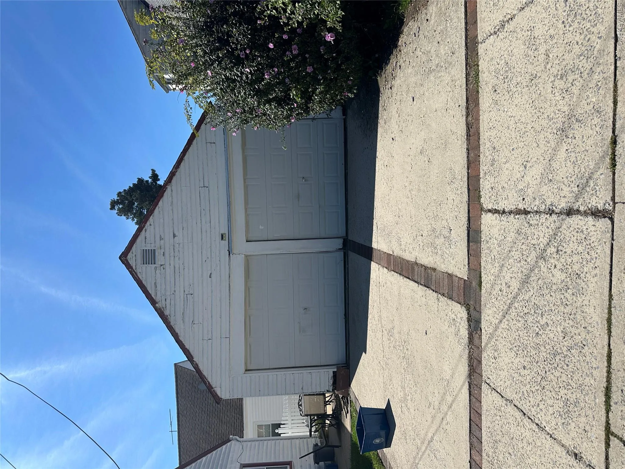 Detached two-car garage with white paneled doors and a gabled roofline Detached two-car garage with white paneled doors and a gabled roofline