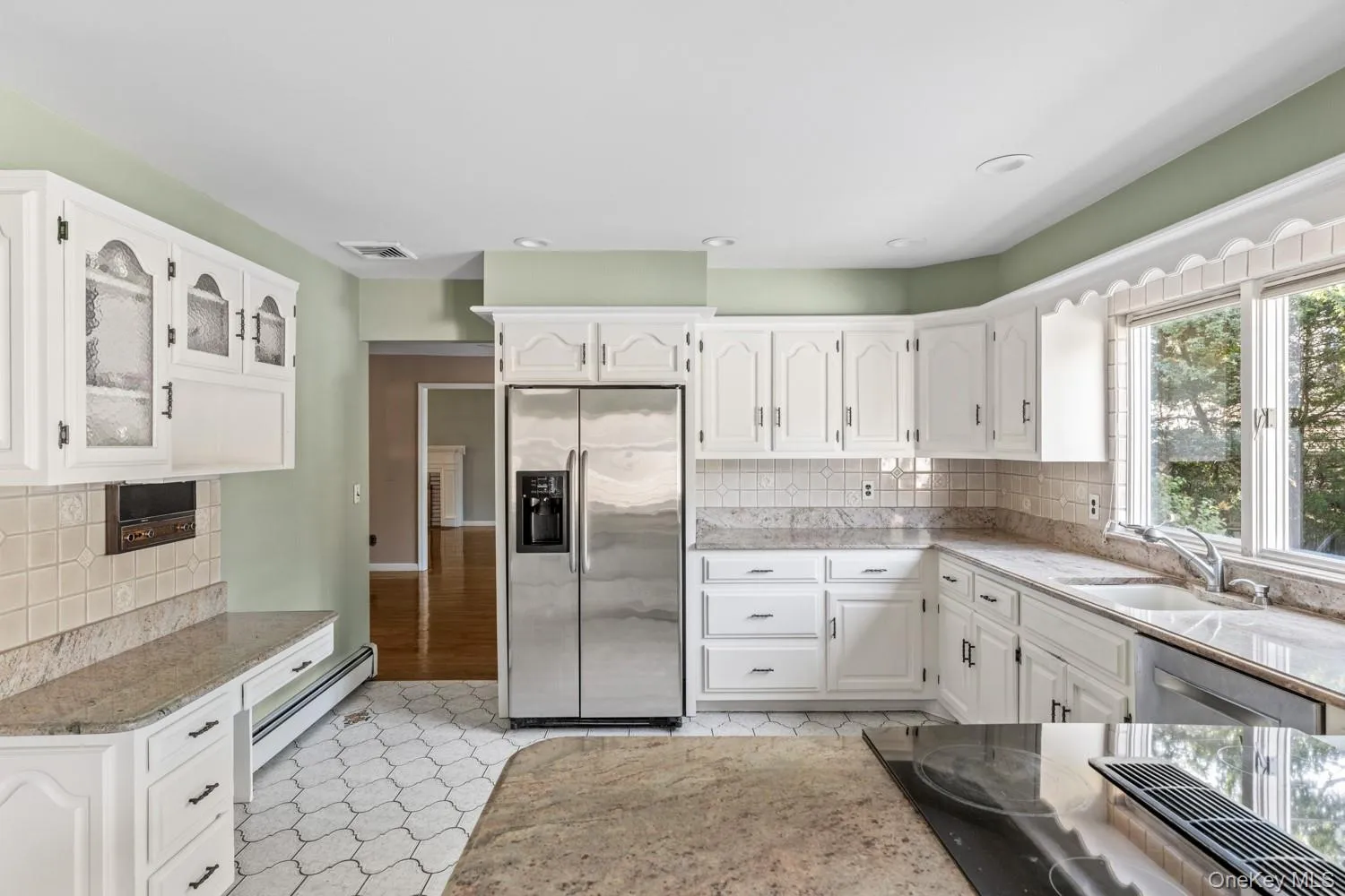 Kitchen with tasteful backsplash, white cabinets, stainless steel appliances, recessed lighting, and light stone counters Kitchen with tasteful backsplash, white cabinets, stainless steel appliances, recessed lighting, and light stone counters