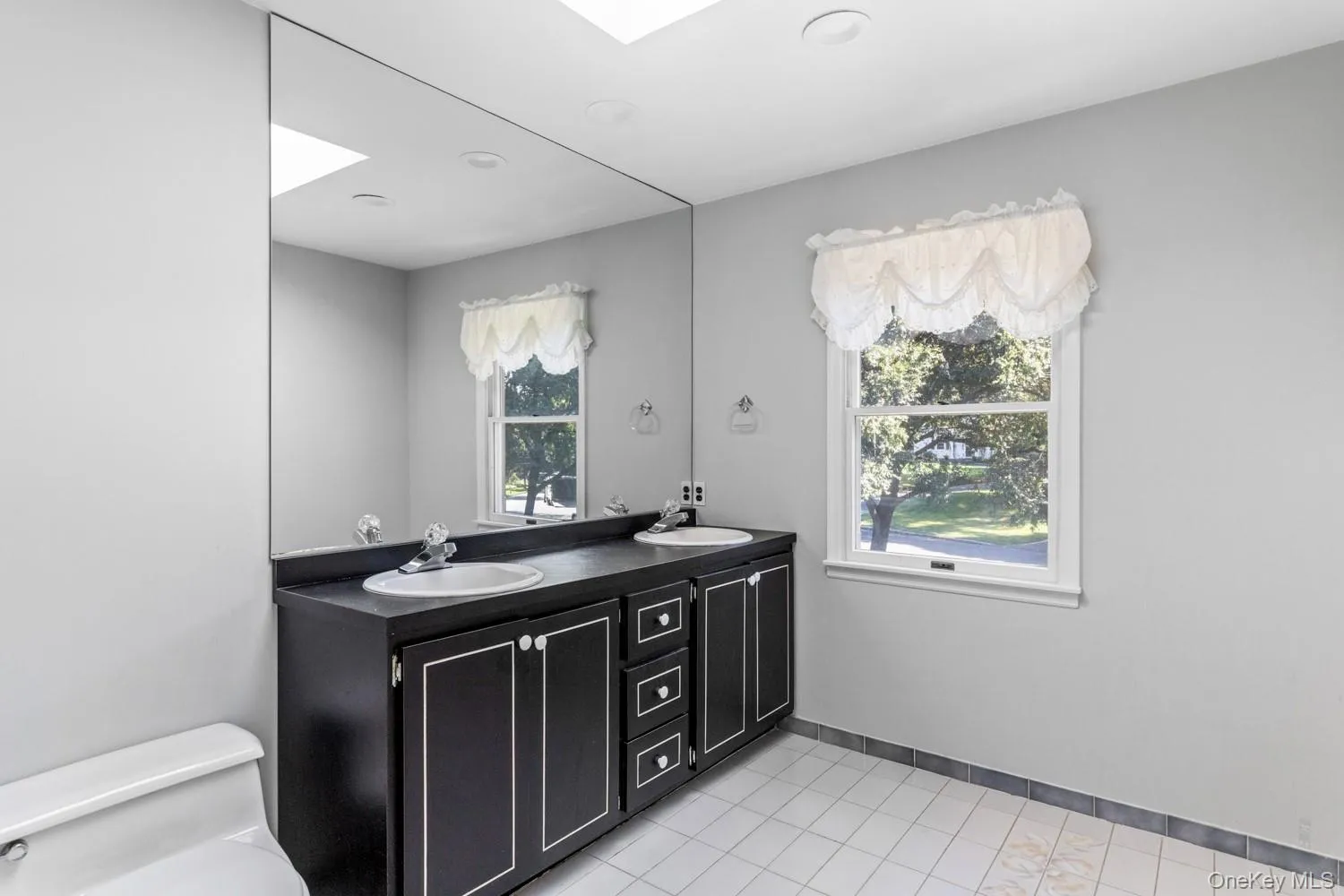 Bathroom featuring light tile patterned floors and double vanity Bathroom featuring light tile patterned floors and double vanity
