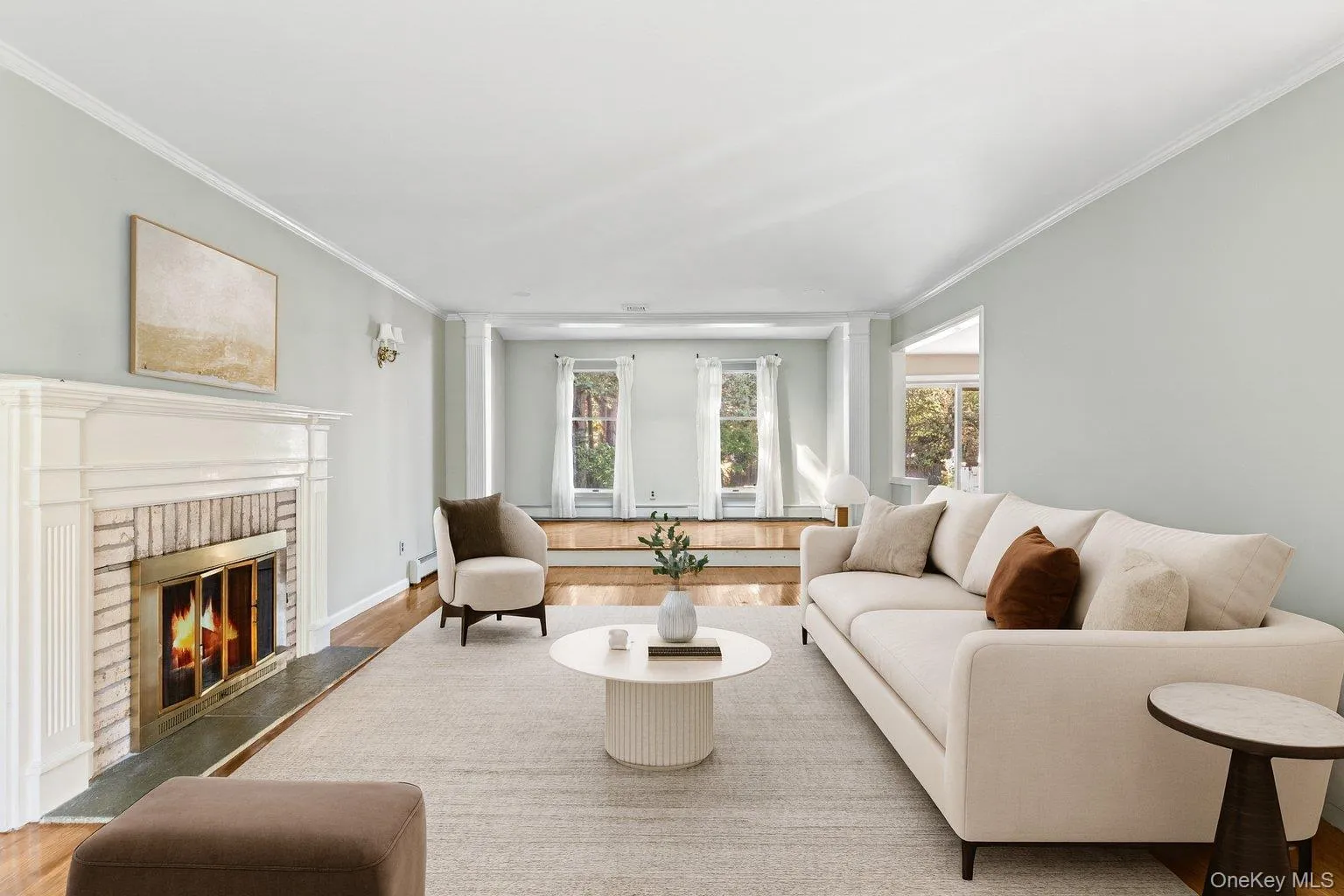 Living room featuring ornamental molding, wood finished floors, and a fireplace Living room featuring ornamental molding, wood finished floors, and a fireplace