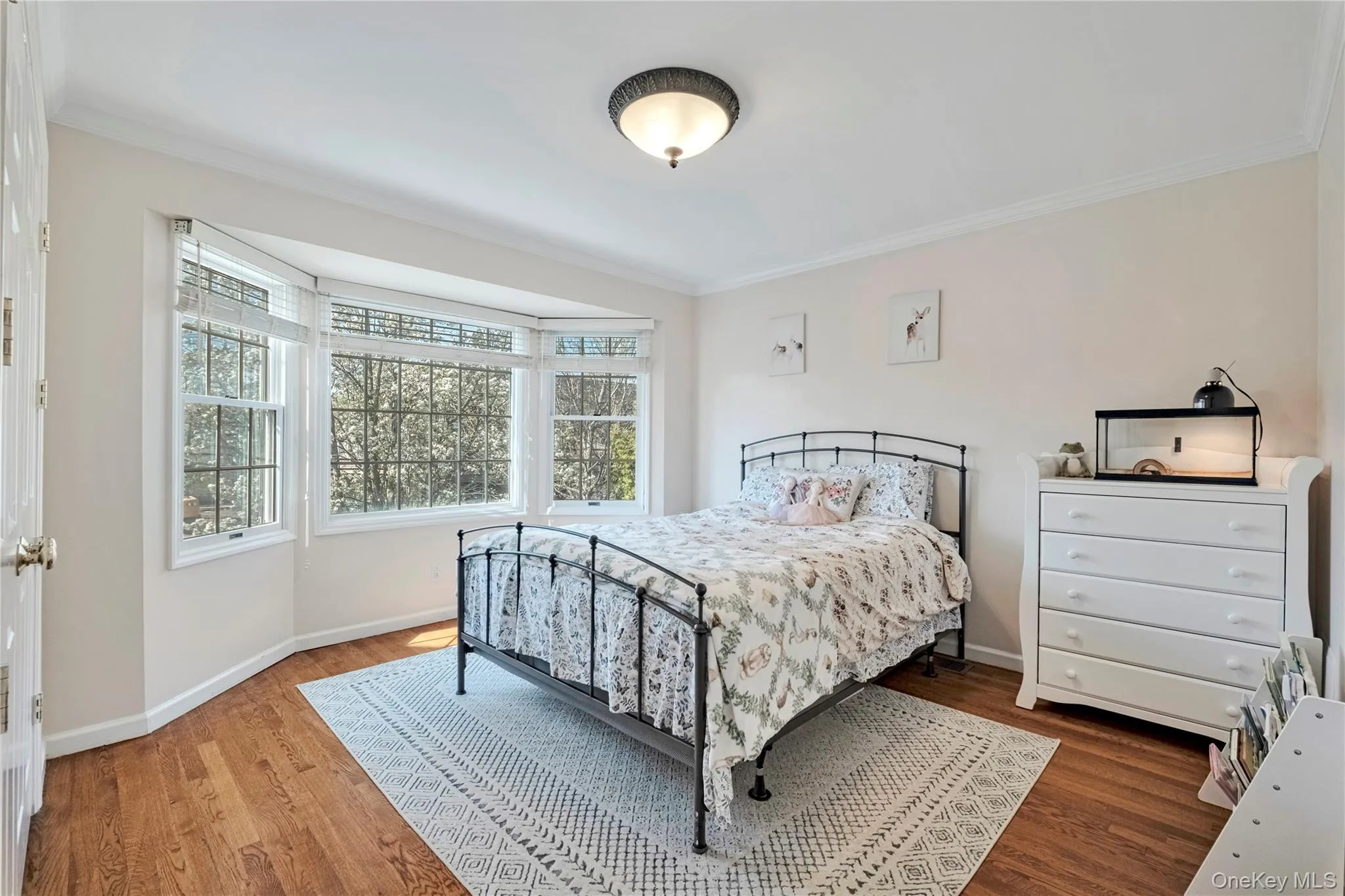 Bedroom with ornamental molding and wood finished floors Bedroom with ornamental molding and wood finished floors
