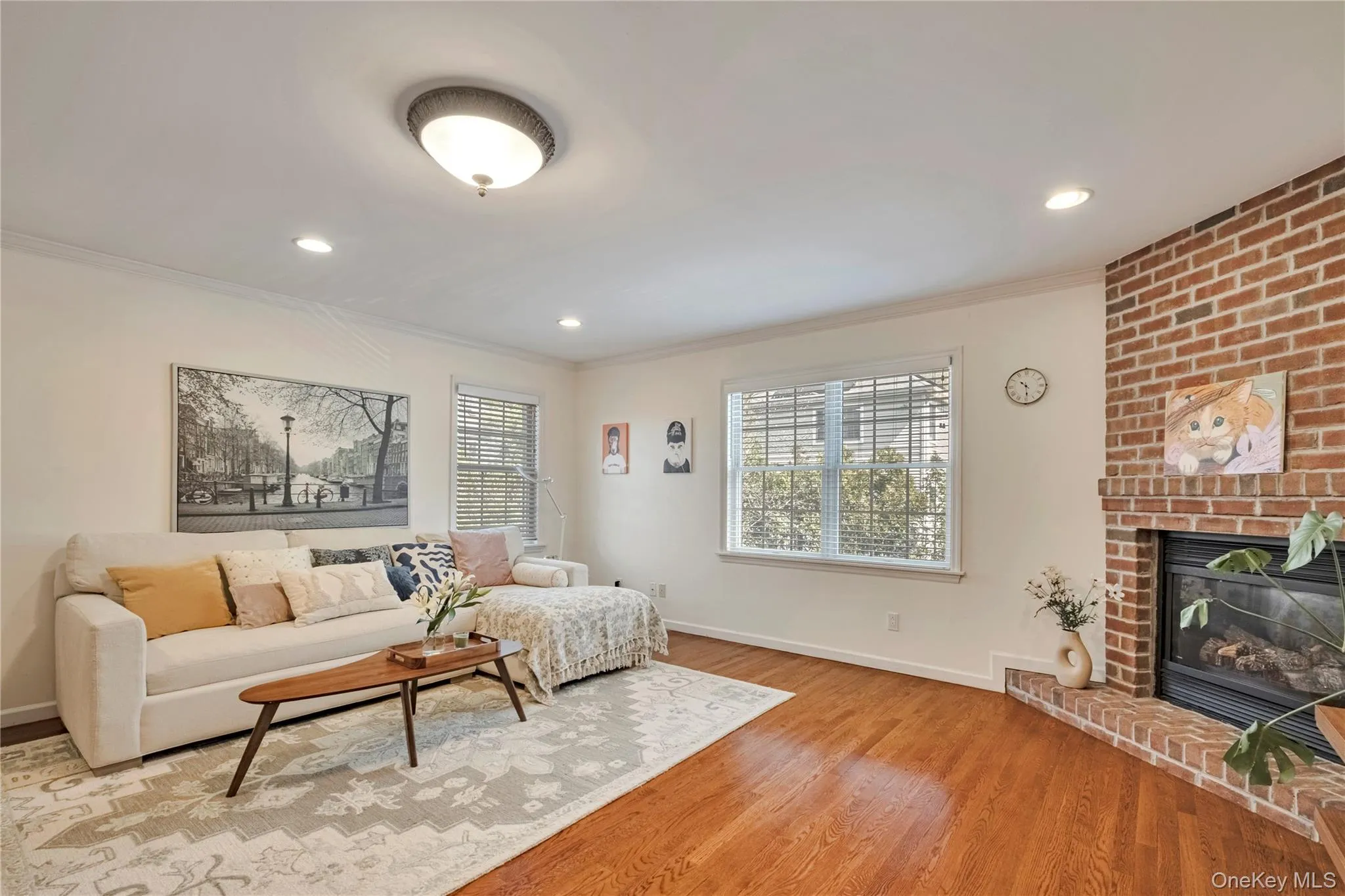 Living room featuring ornamental molding, light wood-style flooring, a fireplace, and recessed lighting Living room featuring ornamental molding, light wood-style flooring, a fireplace, and recessed lighting