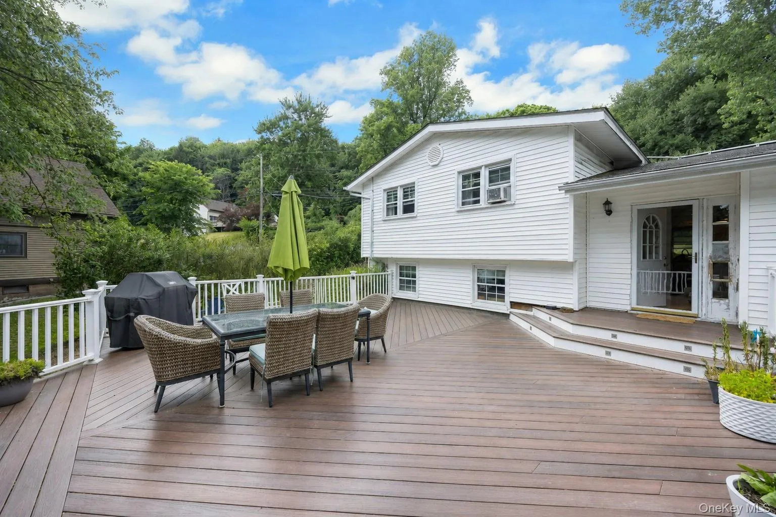 Expansive multi-level wood-finish deck featuring white railings, integrated step lighting, and direct access to the interior Expansive multi-level wood-finish deck featuring white railings, integrated step lighting, and direct access to the interior