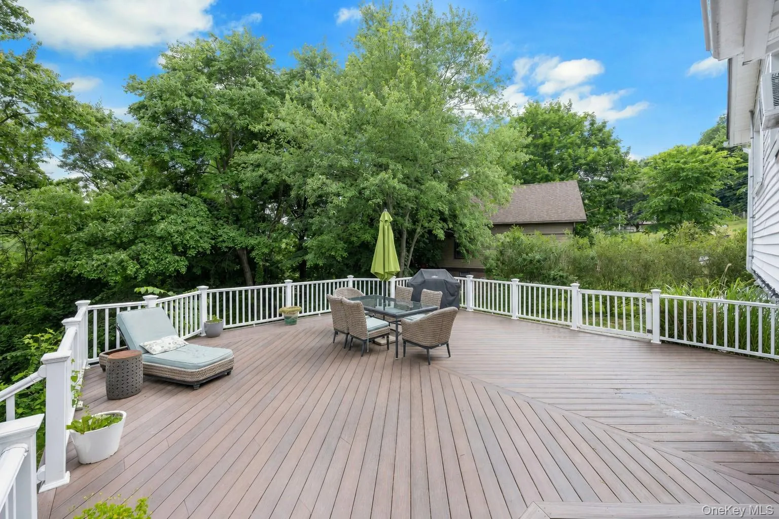 Spacious multi-level deck featuring composite wood-finish flooring and white perimeter railing Spacious multi-level deck featuring composite wood-finish flooring and white perimeter railing