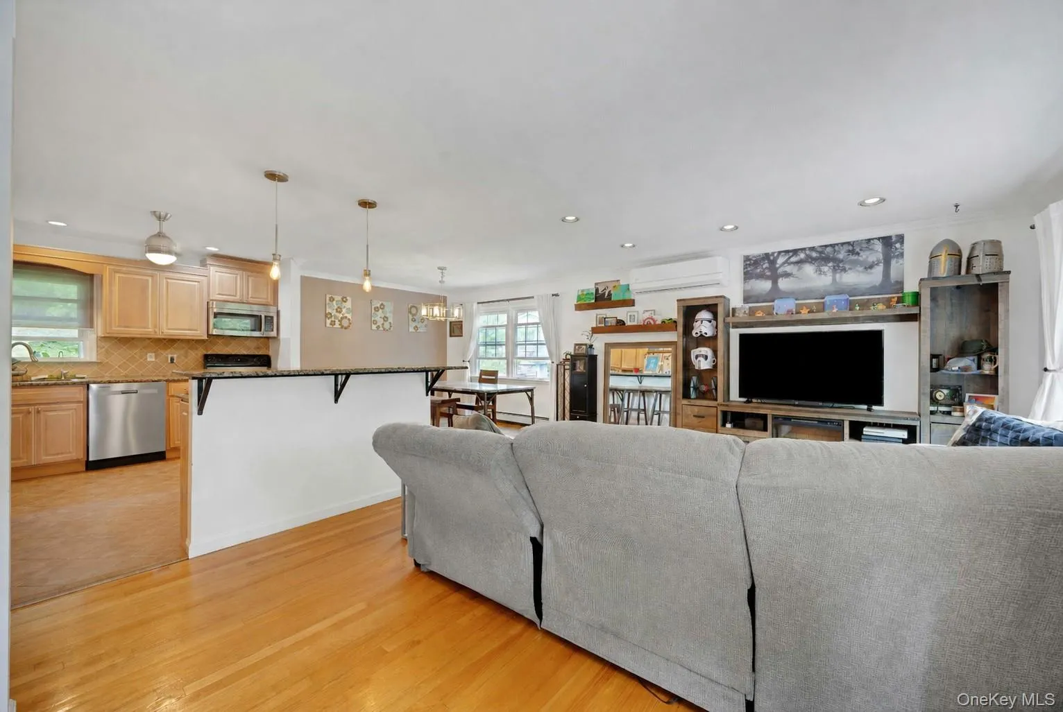 Hardwood flooring spans the open-concept living area, featuring recessed lighting and a built-in media console Hardwood flooring spans the open-concept living area, featuring recessed lighting and a built-in media console