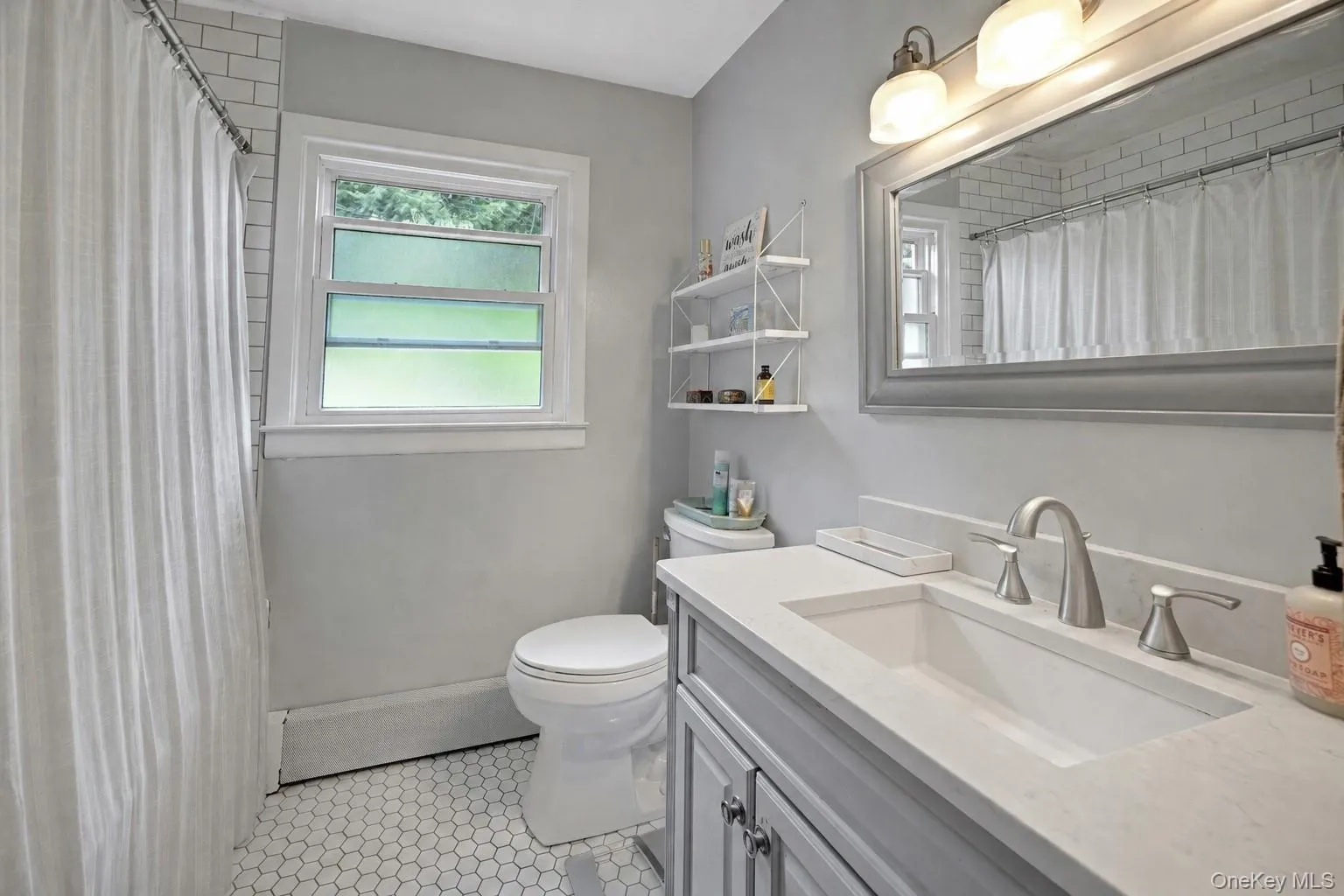 Bathroom featuring a single vanity with an integrated sink, brushed nickel faucet, and a light-toned countertop Bathroom featuring a single vanity with an integrated sink, brushed nickel faucet, and a light-toned countertop