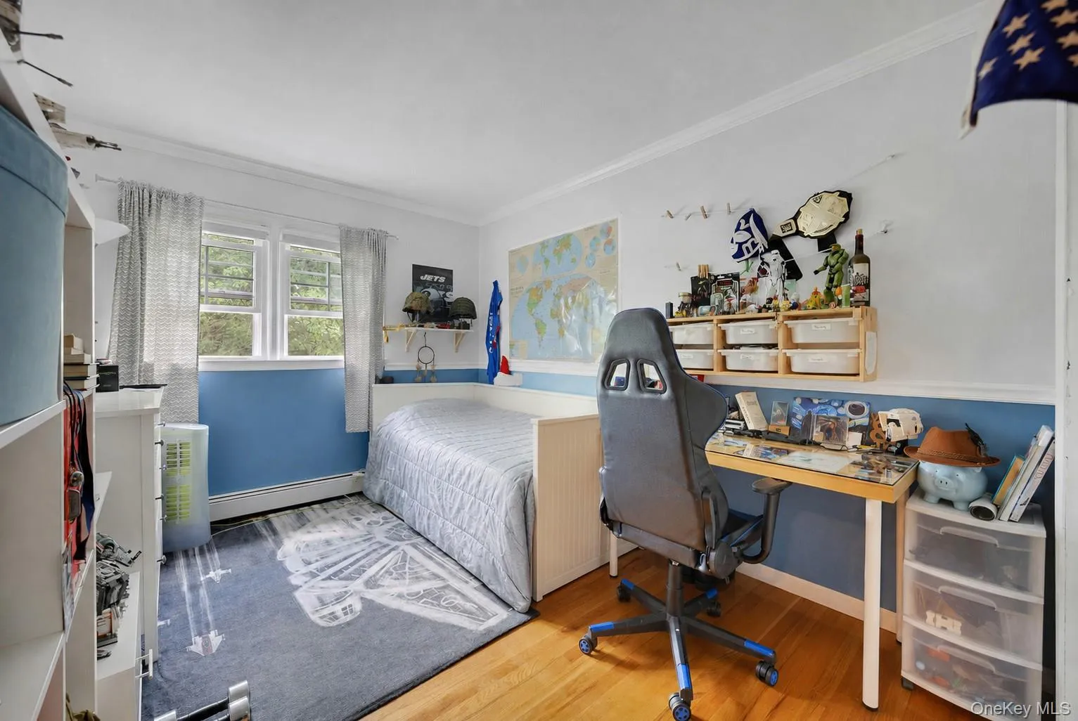 Hardwood flooring complements the bright wall colors in this bedroom, featuring a large window with natural light, a built-in desk, and shelving Hardwood flooring complements the bright wall colors in this bedroom, featuring a large window with natural light, a built-in desk, and shelving