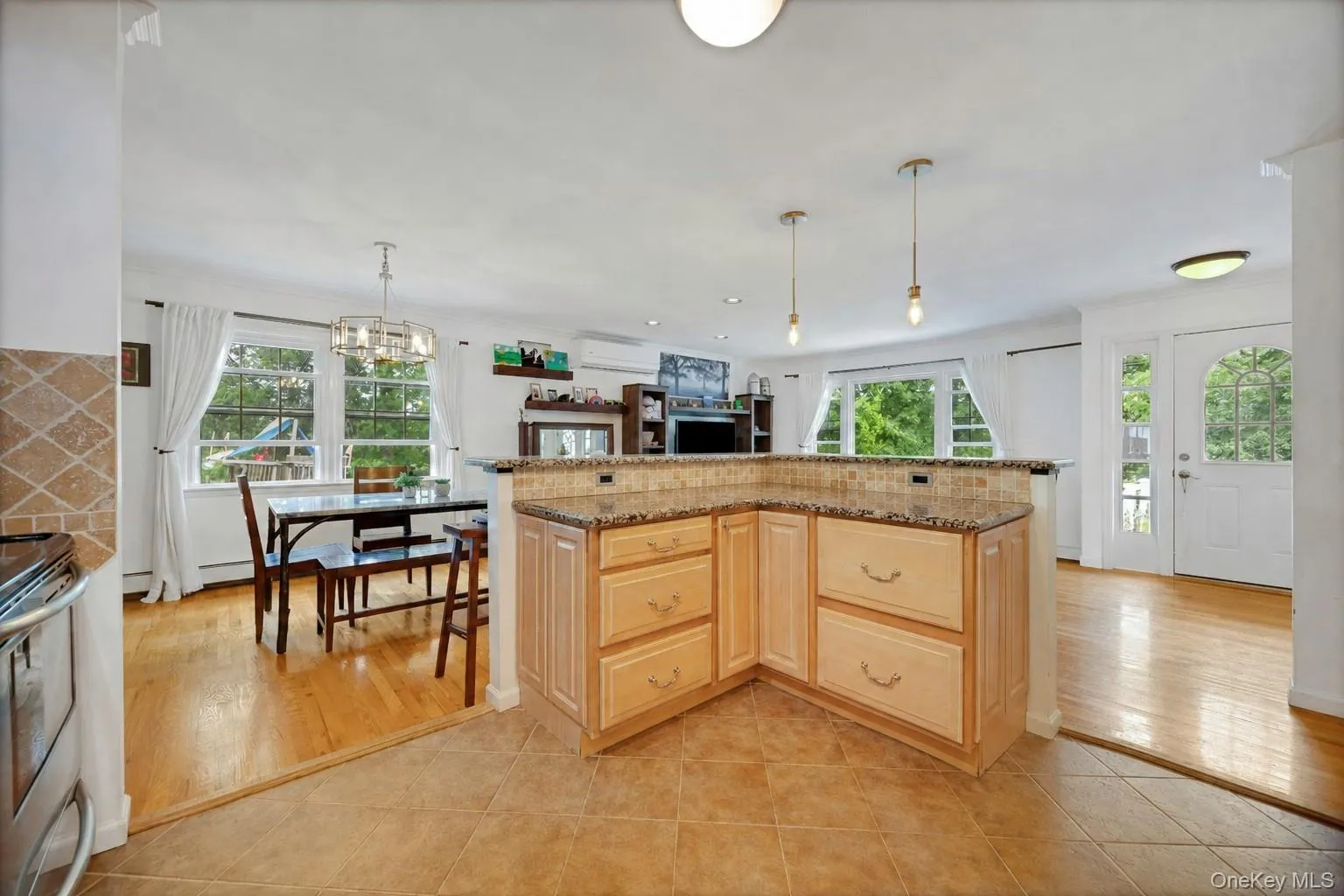 Kitchen featuring a corner breakfast bar with a tile and stone-look countertop, light wood cabinetry, and tile flooring Kitchen featuring a corner breakfast bar with a tile and stone-look countertop, light wood cabinetry, and tile flooring