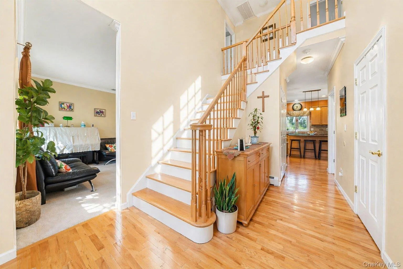 Two-story entryway featuring wood-finish flooring, a wood staircase with balusters, and a recessed lighting fixture Two-story entryway featuring wood-finish flooring, a wood staircase with balusters, and a recessed lighting fixture