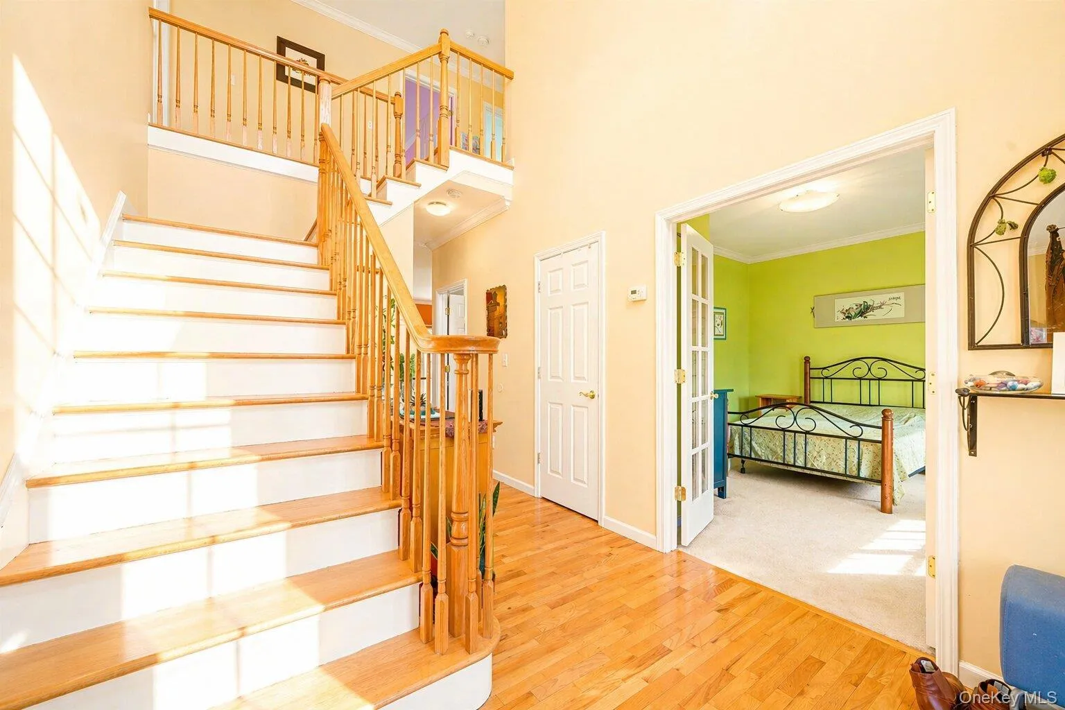 Two-story entryway featuring wood-finish flooring, a staircase with wood-finish treads and white risers, and a coordinating wood railing with turned balusters Two-story entryway featuring wood-finish flooring, a staircase with wood-finish treads and white risers, and a coordinating wood railing with turned balusters