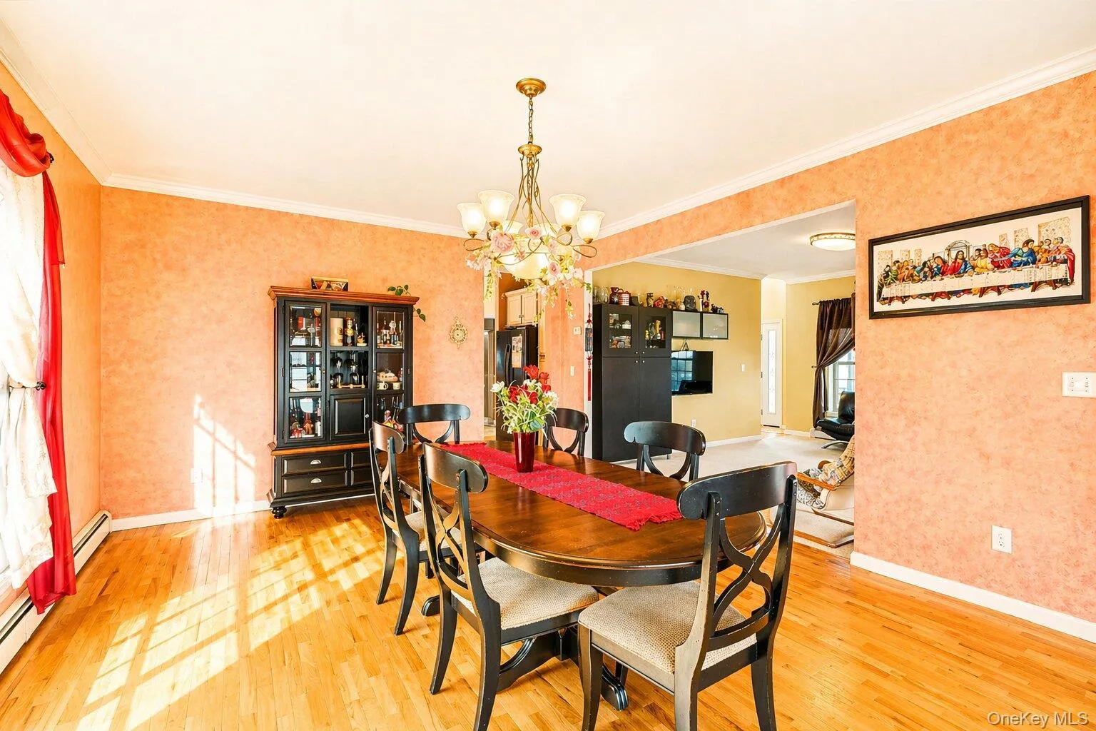 Bright room featuring wood-finish flooring, a decorative chandelier, crown molding, and an open doorway to an additional room Bright room featuring wood-finish flooring, a decorative chandelier, crown molding, and an open doorway to an additional room