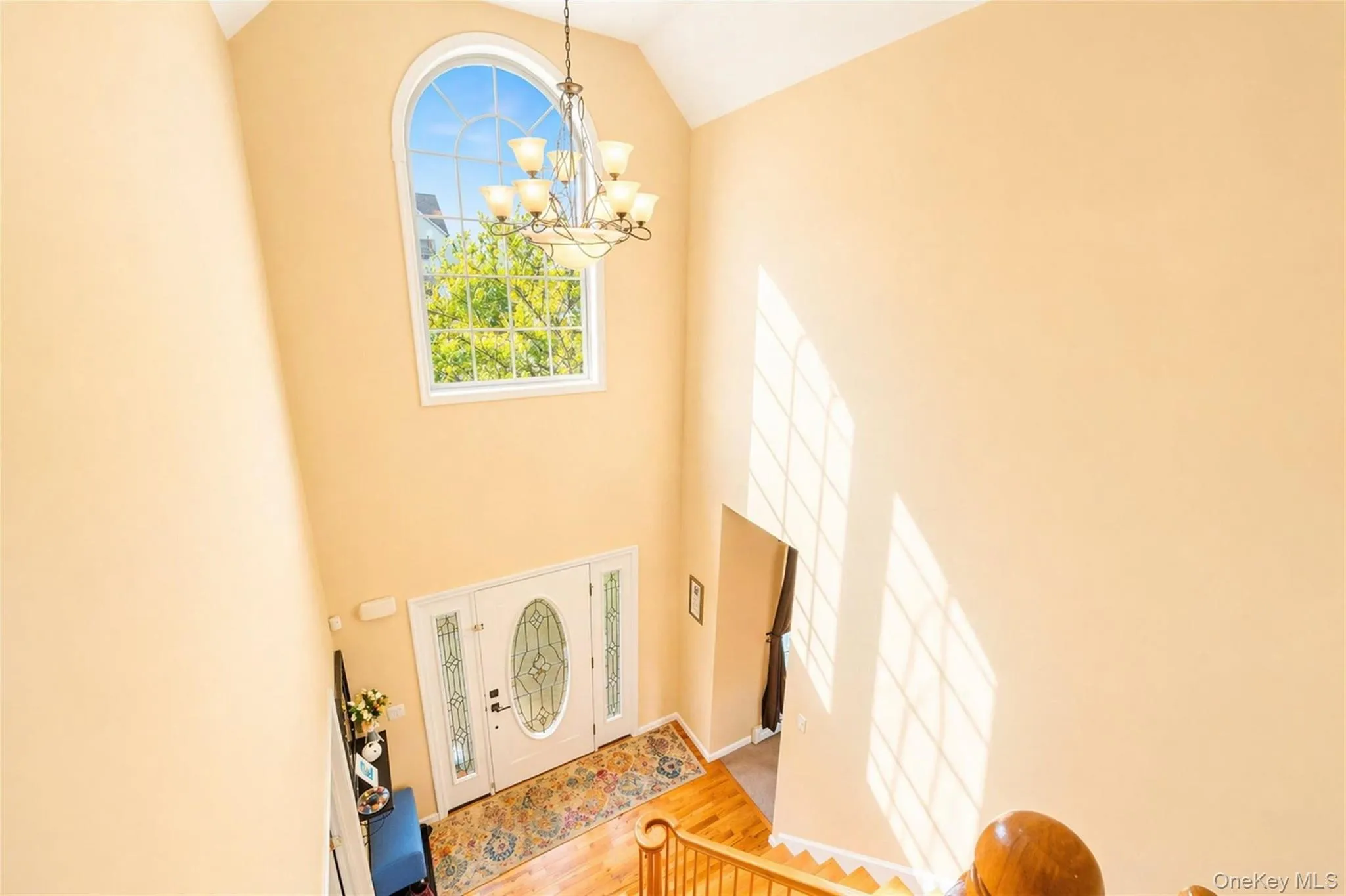 Two-story foyer featuring an arched window, decorative glass entry door, side lites, and a multi-arm chandelier Two-story foyer featuring an arched window, decorative glass entry door, side lites, and a multi-arm chandelier