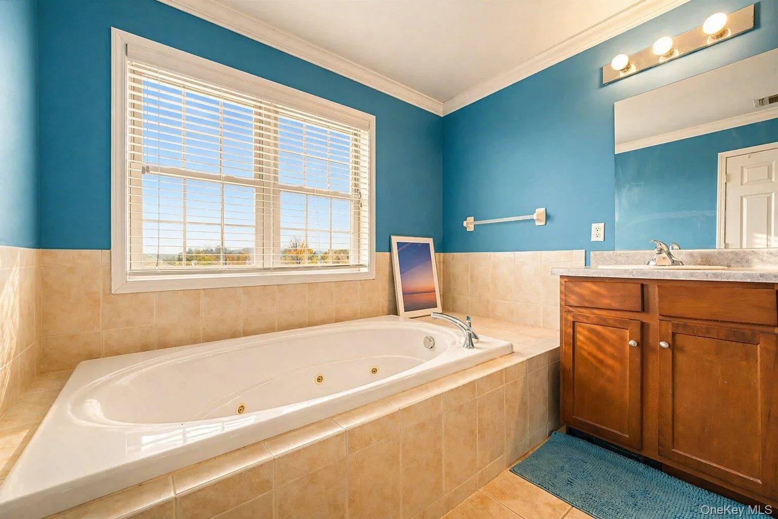 Soaking tub with jetted features, surrounded by tile-finish walls and a large window Soaking tub with jetted features, surrounded by tile-finish walls and a large window