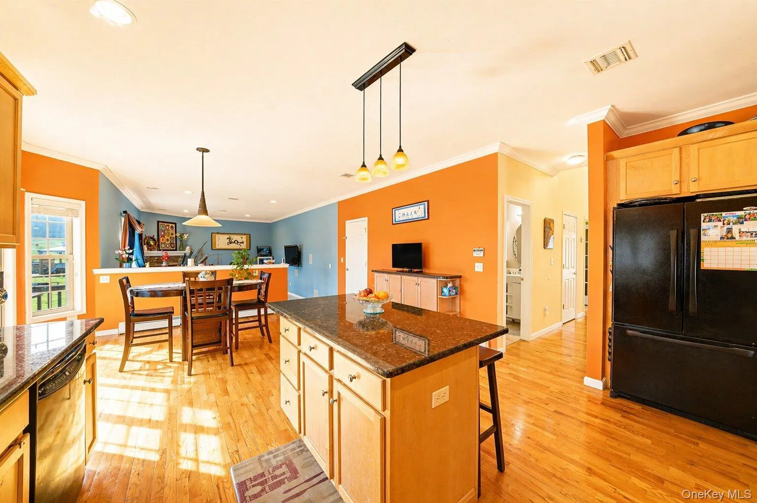 Kitchen featuring a central island with a stone-finish countertop, wood-finish flooring, and light wood cabinetry Kitchen featuring a central island with a stone-finish countertop, wood-finish flooring, and light wood cabinetry