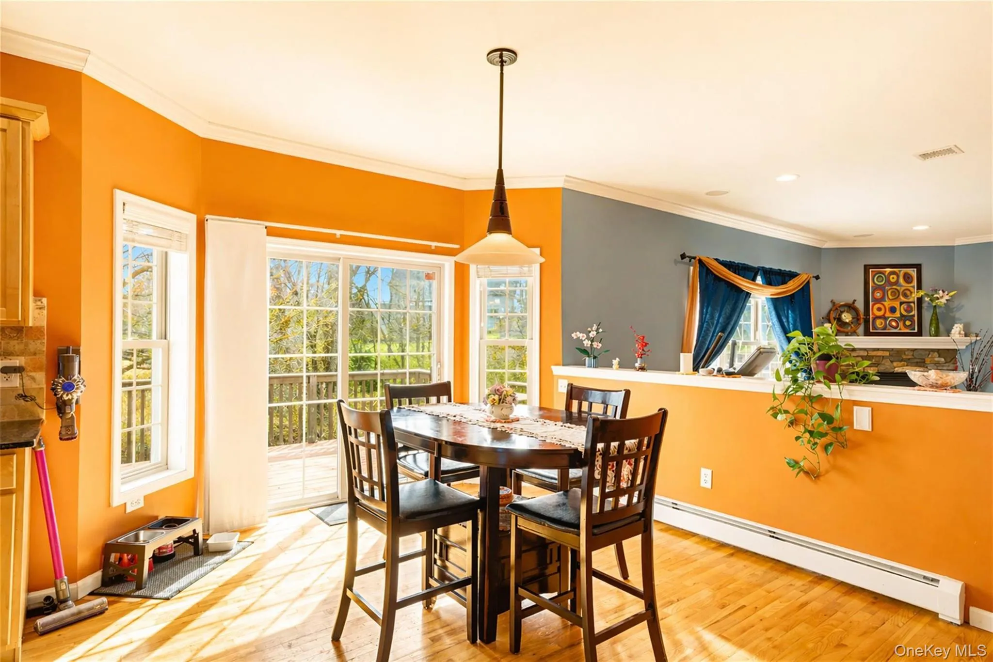 Open-concept kitchen featuring wood-finish flooring, a contemporary pendant light fixture, and crown molding Open-concept kitchen featuring wood-finish flooring, a contemporary pendant light fixture, and crown molding