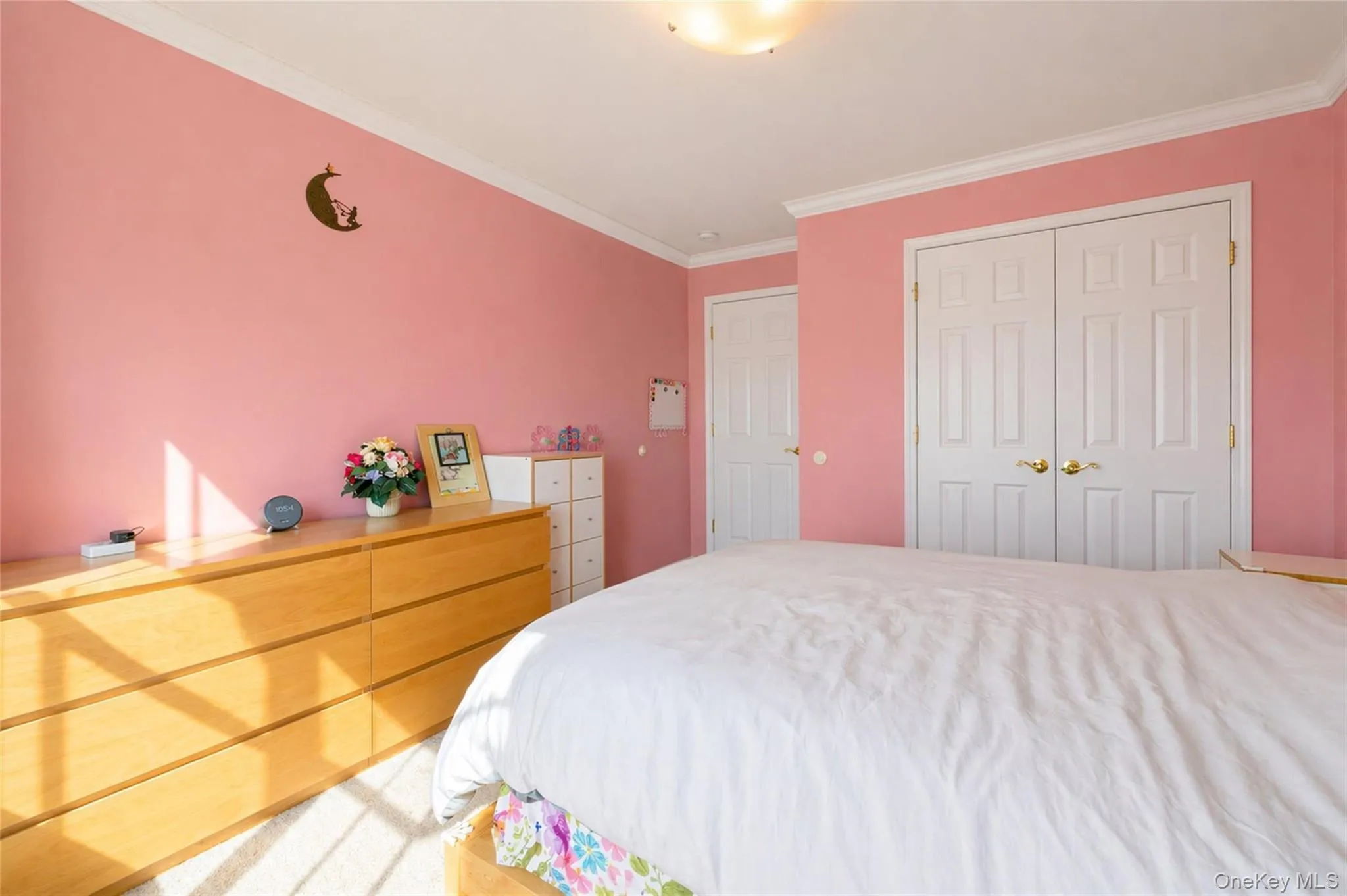Bedroom featuring crown molding, two white paneled doors, and wall-to-wall carpeting Bedroom featuring crown molding, two white paneled doors, and wall-to-wall carpeting