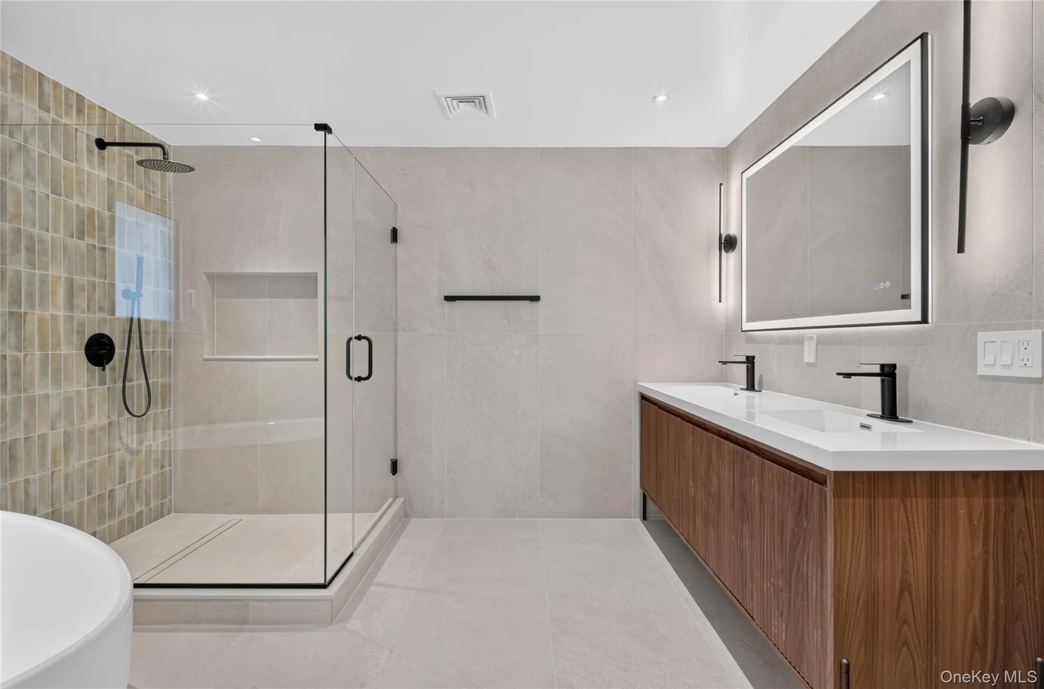 Spacious bathroom featuring a glass-enclosed shower with tiled walls and a built-in niche Spacious bathroom featuring a glass-enclosed shower with tiled walls and a built-in niche