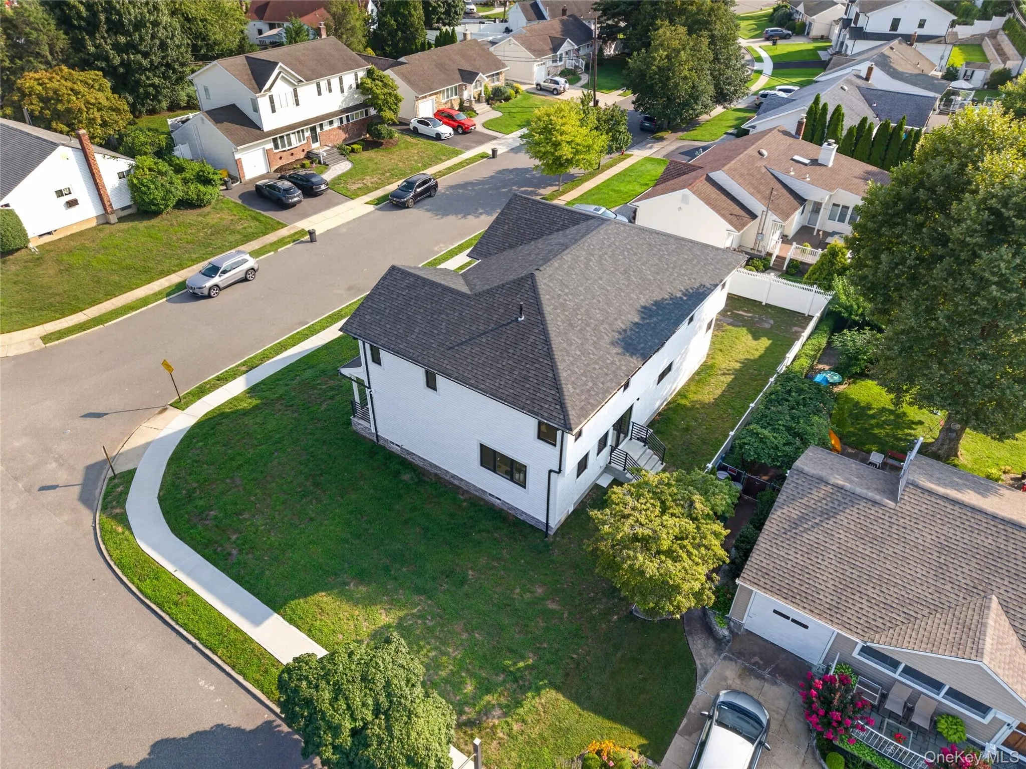 White exterior with black-framed windows, dark shingle roof, and a perimeter fence White exterior with black-framed windows, dark shingle roof, and a perimeter fence
