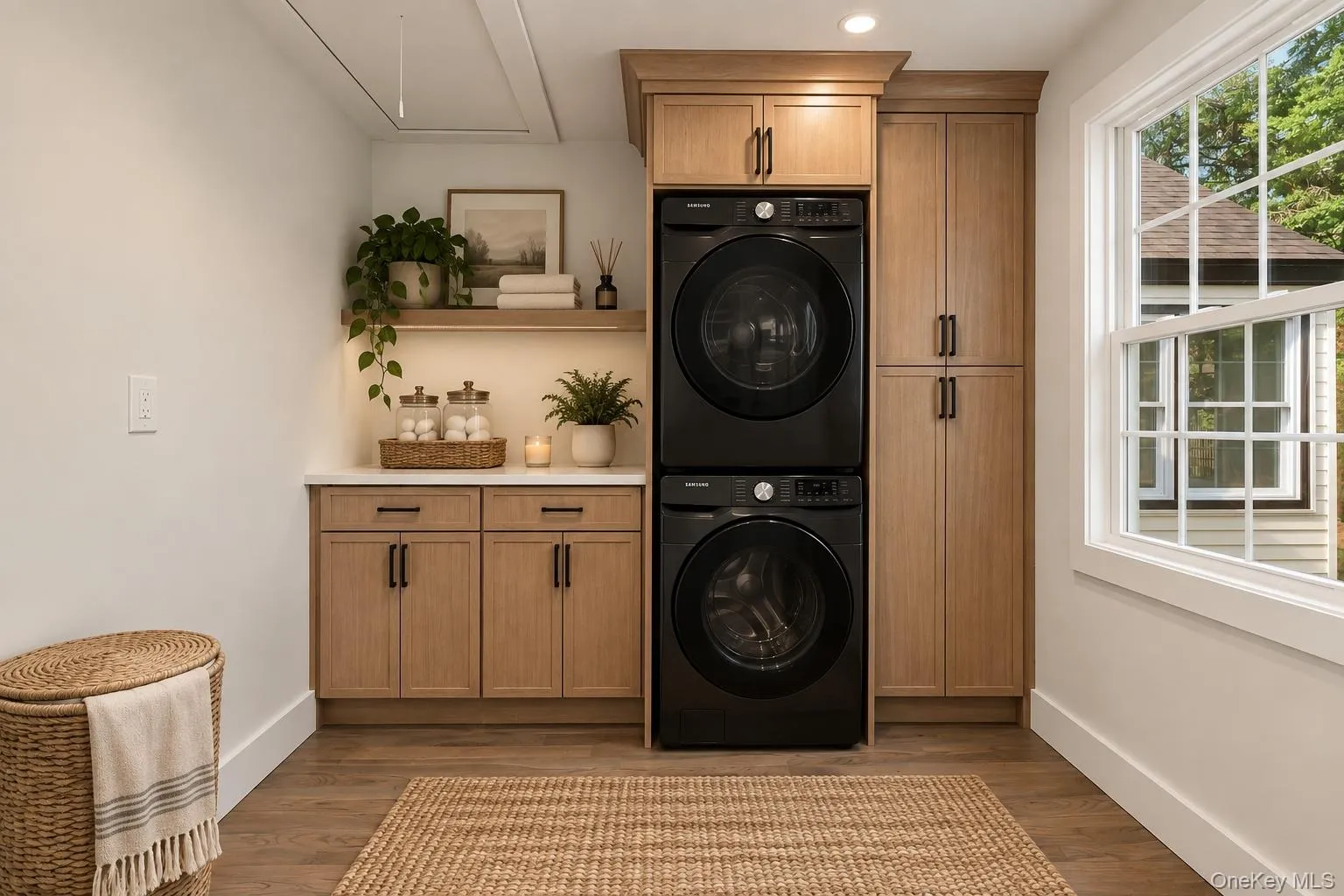 Wood-finish flooring, light wood cabinetry with dark hardware, built-in shelving with integrated lighting, and a white framed window Wood-finish flooring, light wood cabinetry with dark hardware, built-in shelving with integrated lighting, and a white framed window