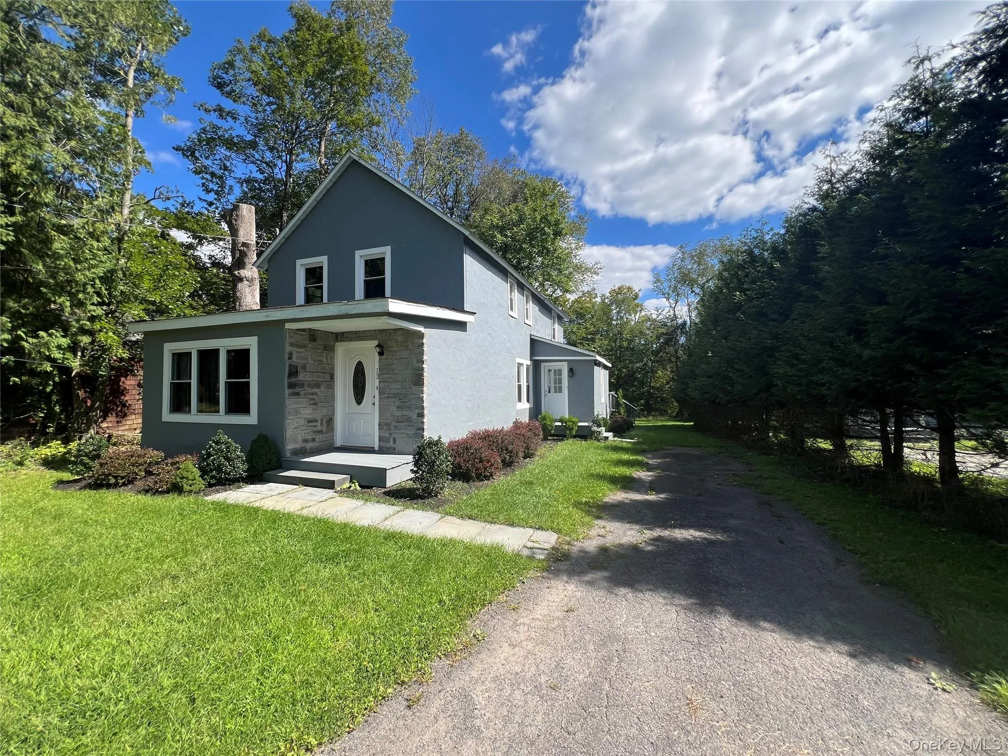 Two-story exterior with a stone and siding facade, a front porch, and a gravel driveway Two-story exterior with a stone and siding facade, a front porch, and a gravel driveway